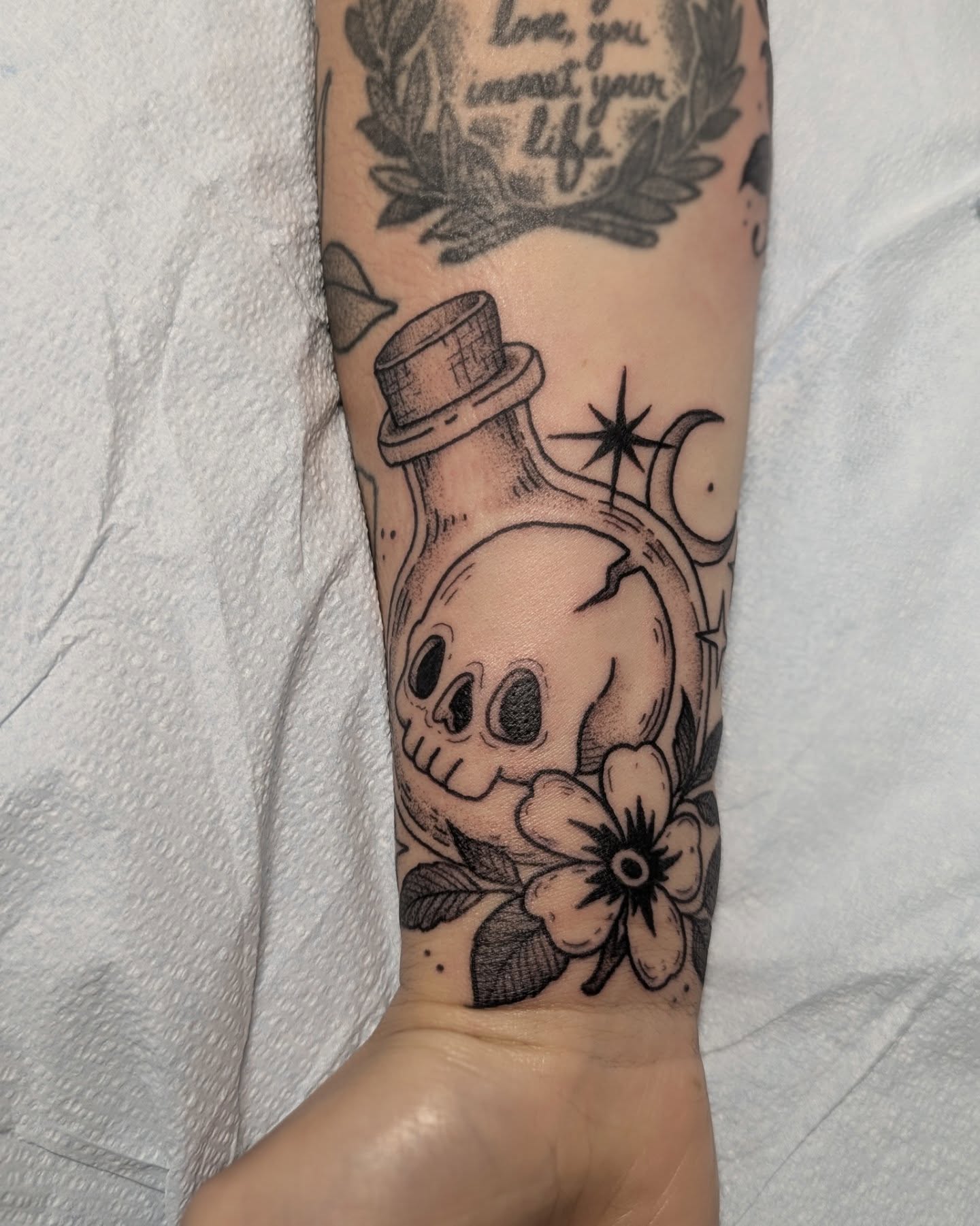 Skull in bottle black and grey tattoo on the forearm by Dani Harkey