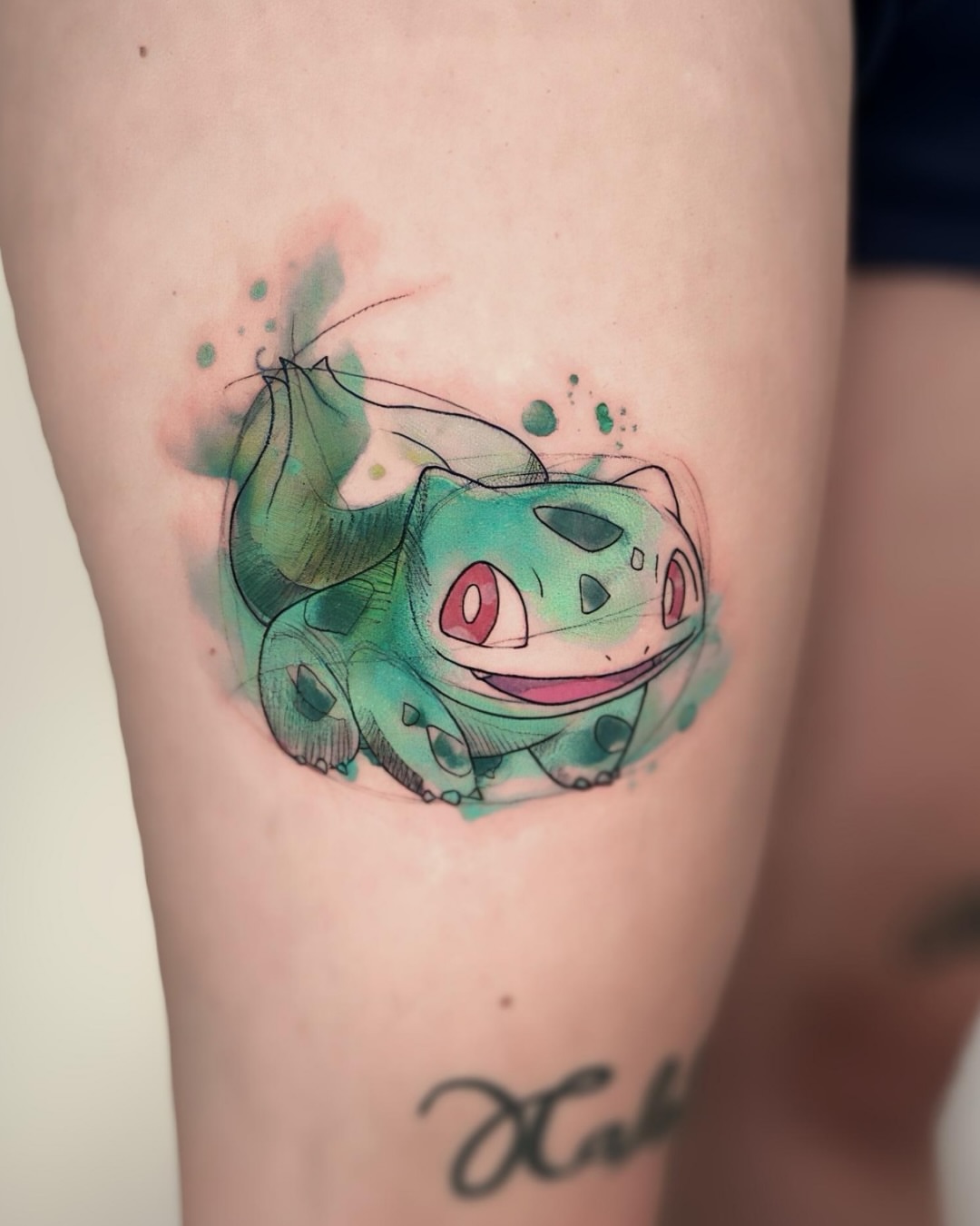 Bulbasaur watercolor tattoo on the thigh by Jen Rahman