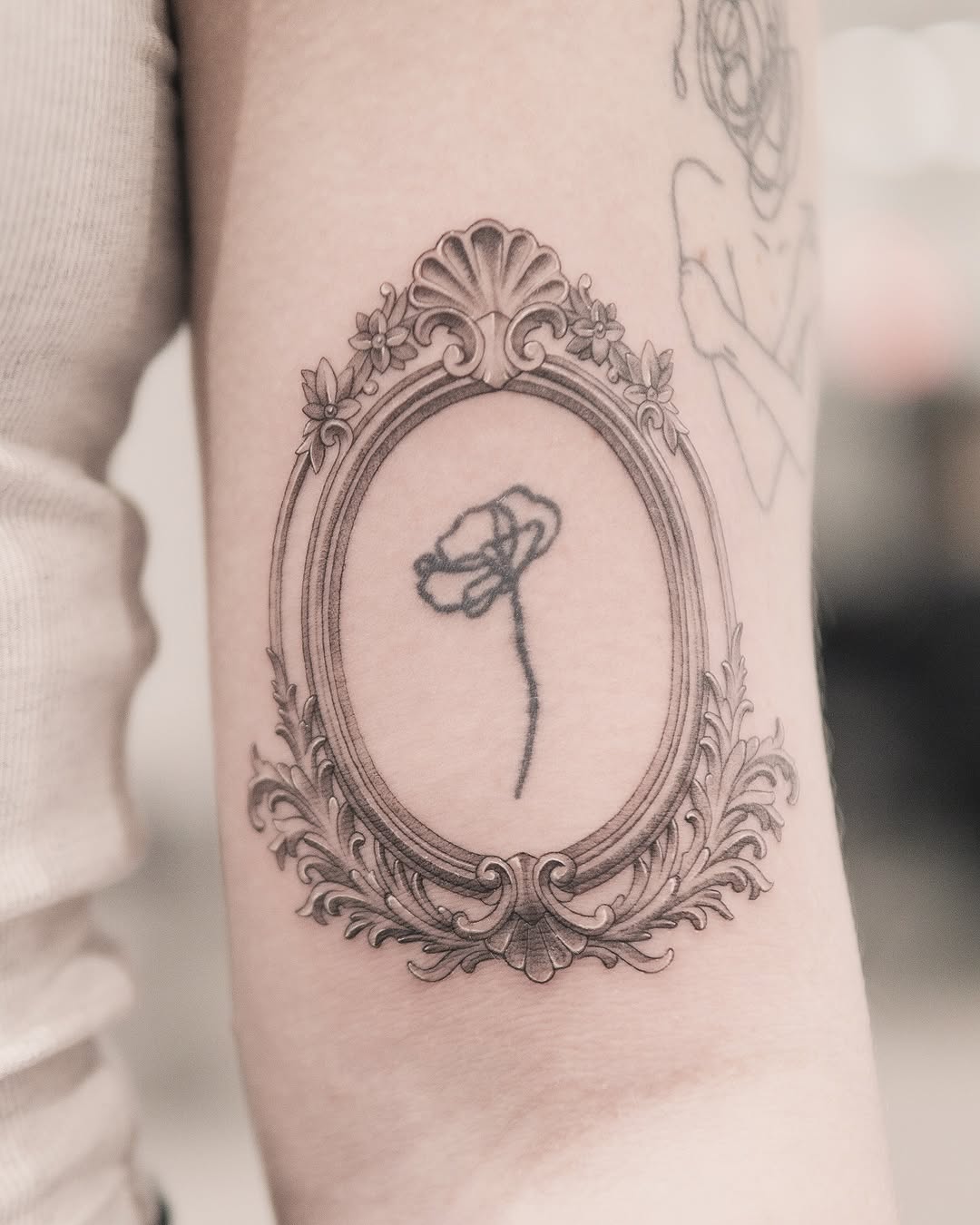 Ornate frame with flower fine line tattoo on the forearm by Joey