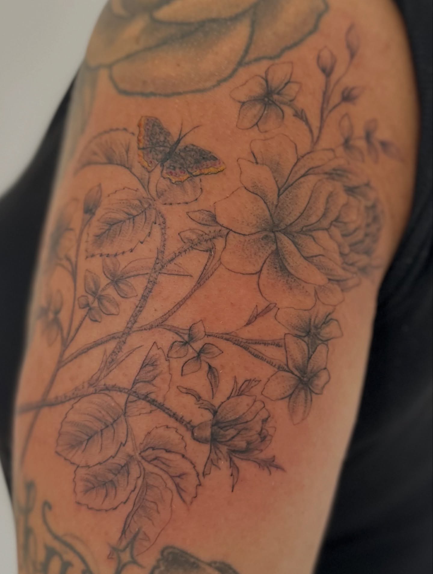 Flowers and butterfly realism tattoo on the upper arm by Ric Castellon Tattoo Artist, Los Angeles, California