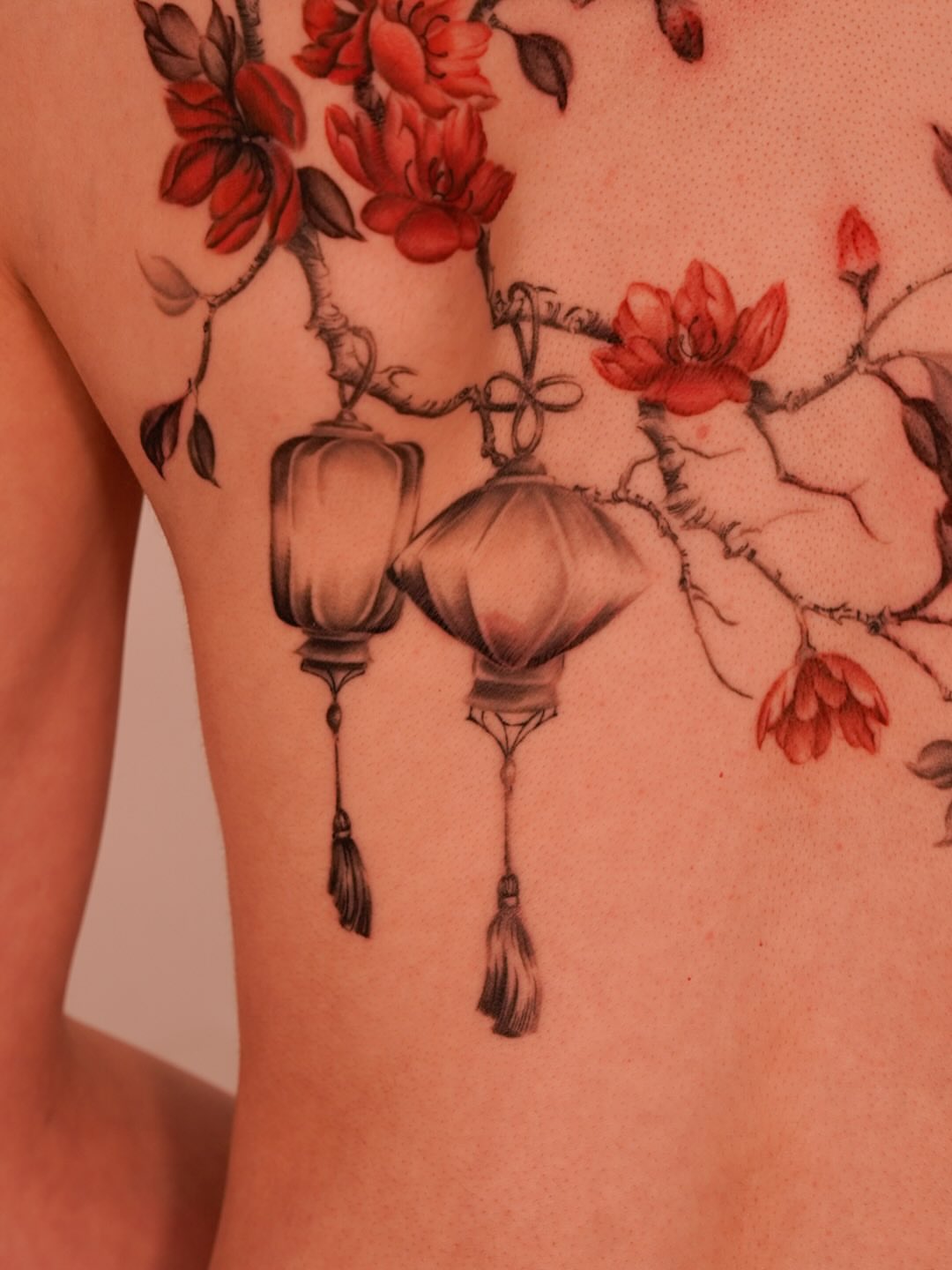 Cherry blossoms and lanterns realism tattoo on the chest by Nicki Yến