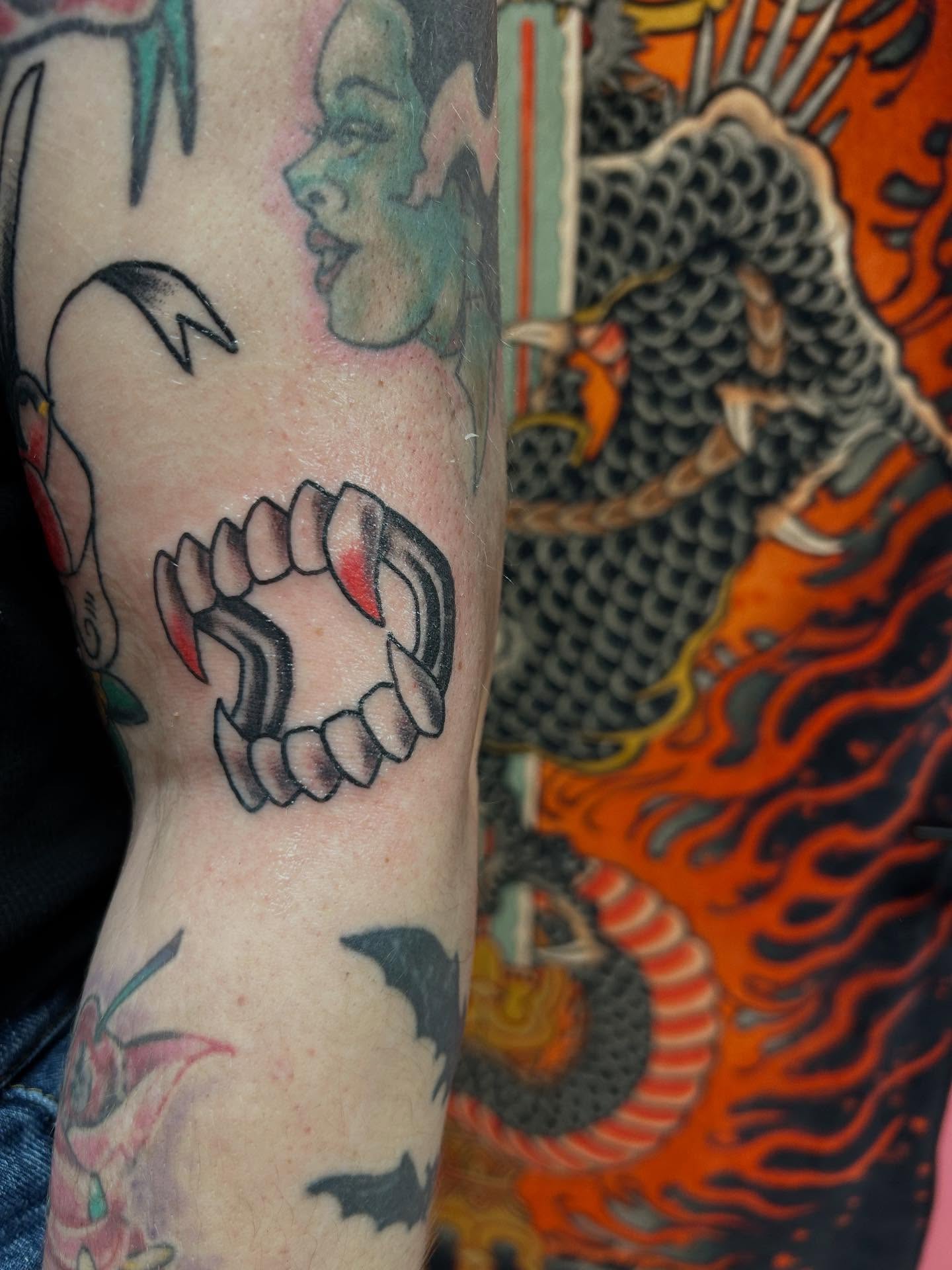 Fangs American traditional tattoo on the forearm by Stogie Tony