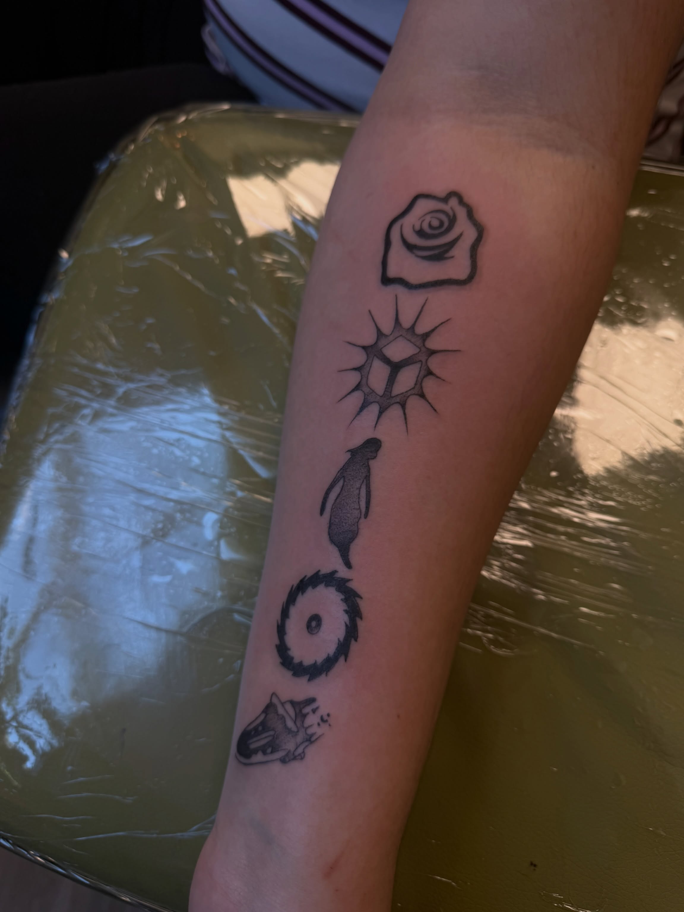 Rose, sun, penguin, gear, wolf black and grey tattoo on the forearm by ashlyn rene