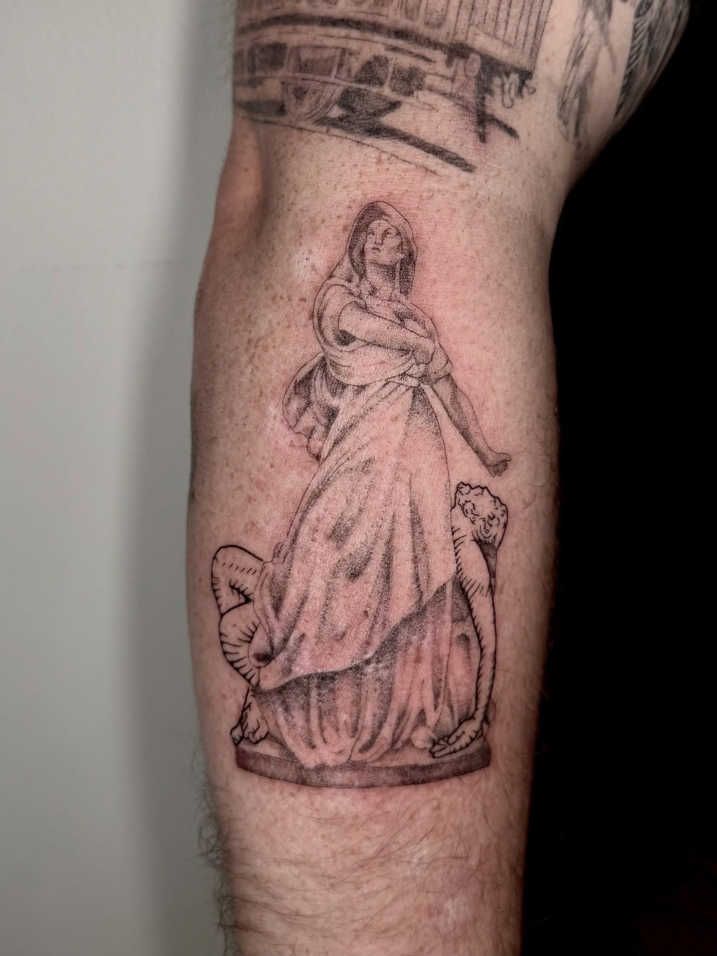 Statue with cat black and grey tattoo on the forearm by Ian Saner