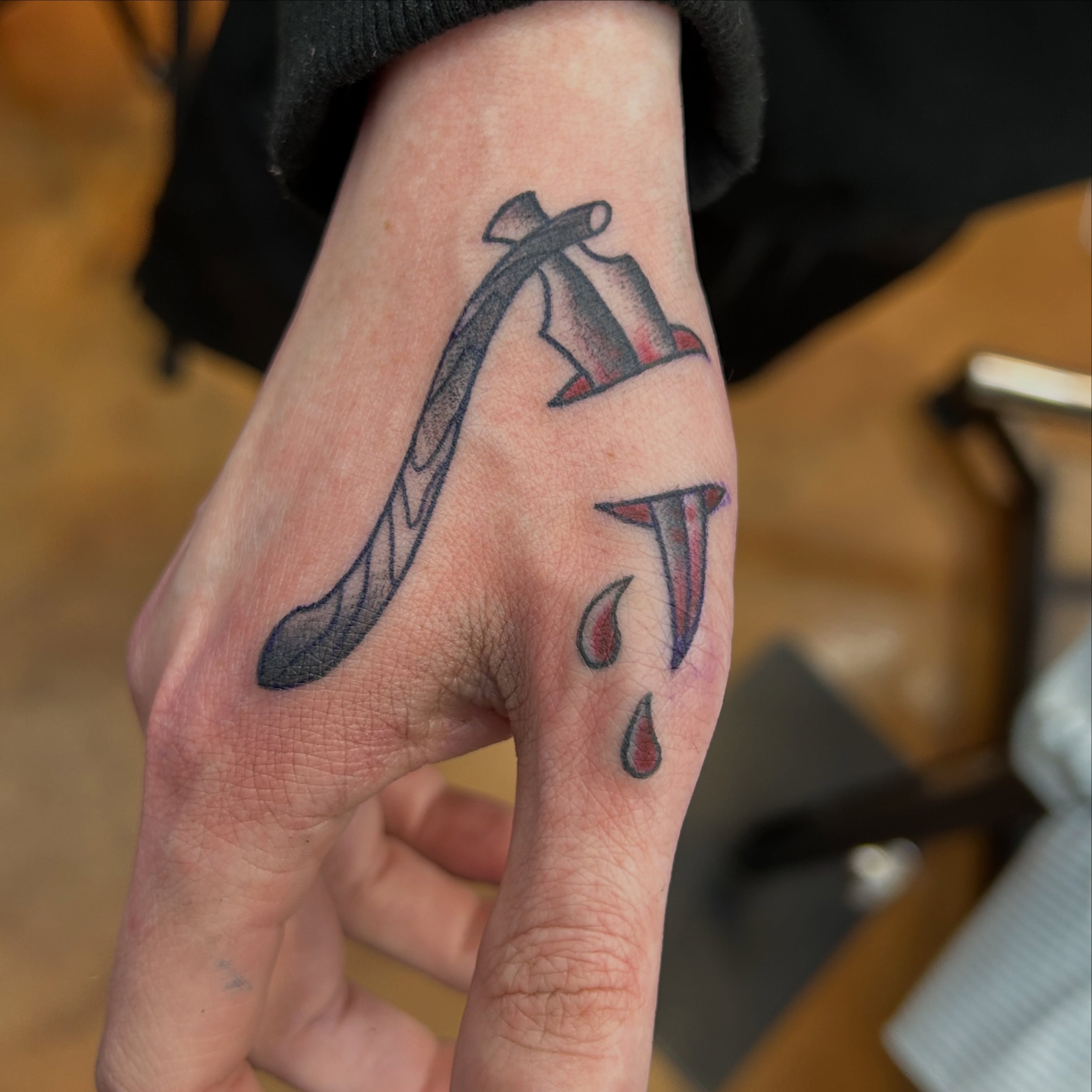 Knife and blood black and grey tattoo on the hand by Alex Byrne