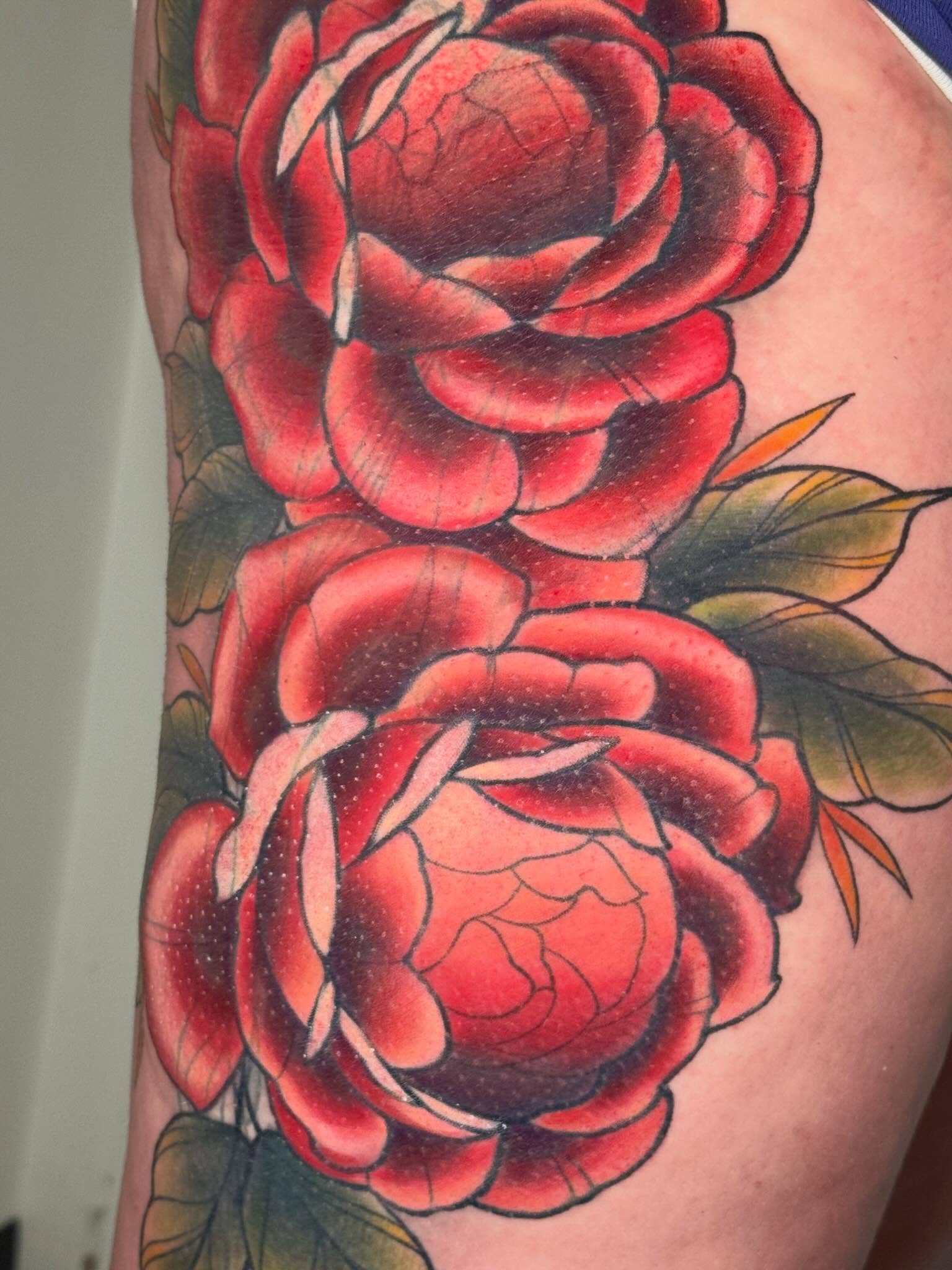Red roses American traditional tattoo on the upper arm by Kayla Warren