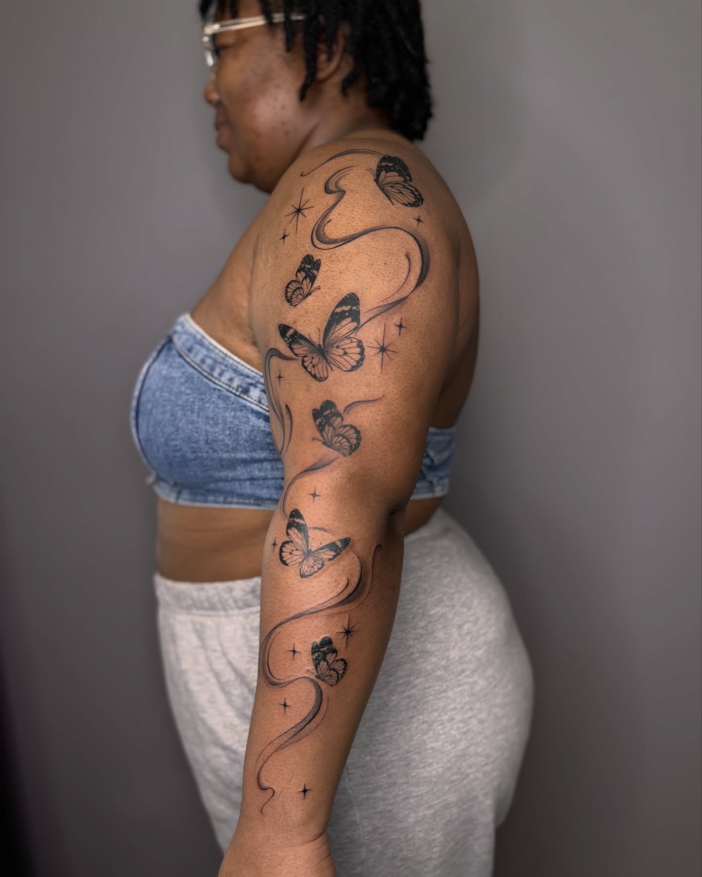 Butterflies black and grey tattoo on the upper arm by Suzy