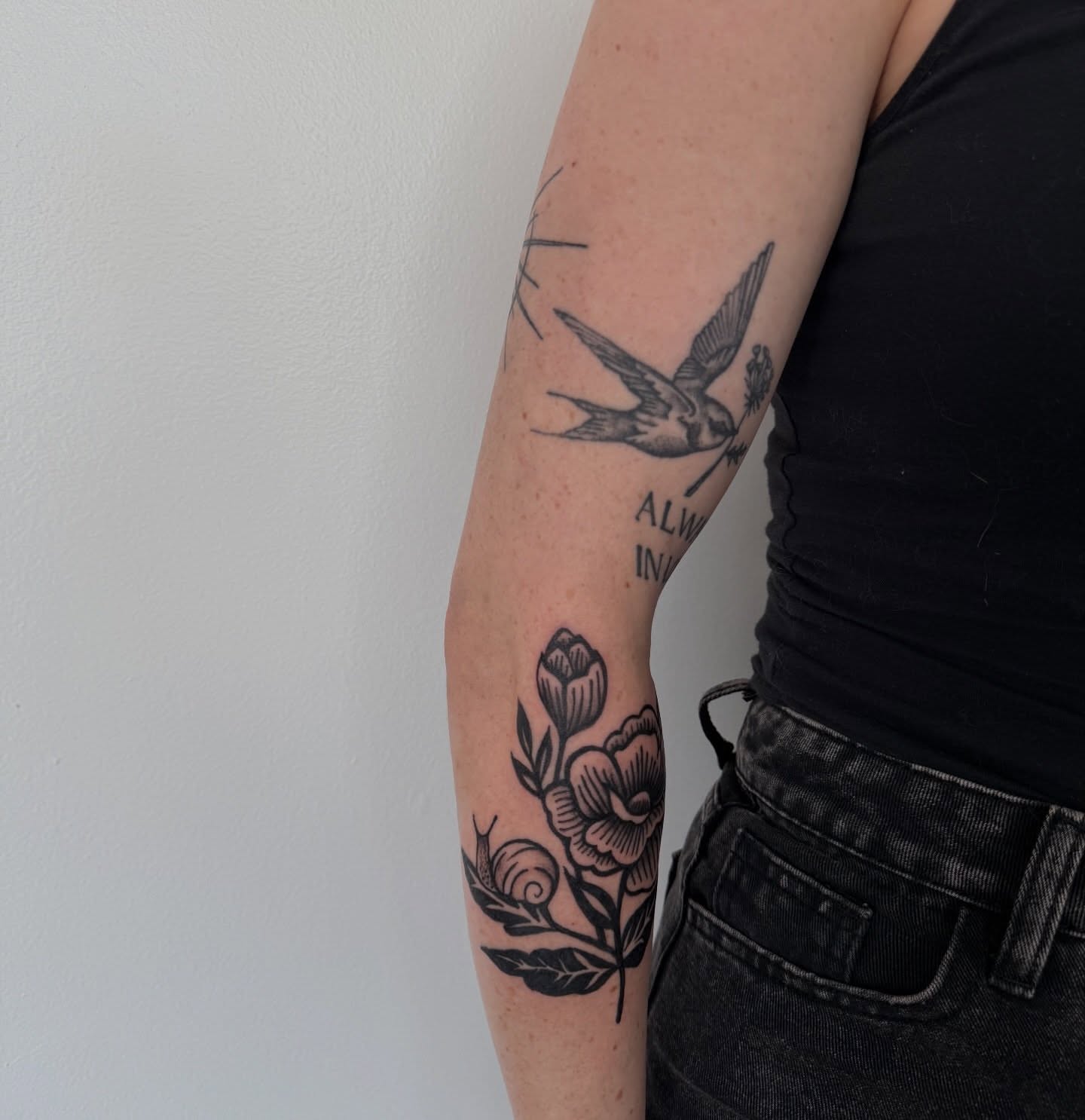 Swallow and flowers black and grey tattoo on the forearm by Lindsay Shriver