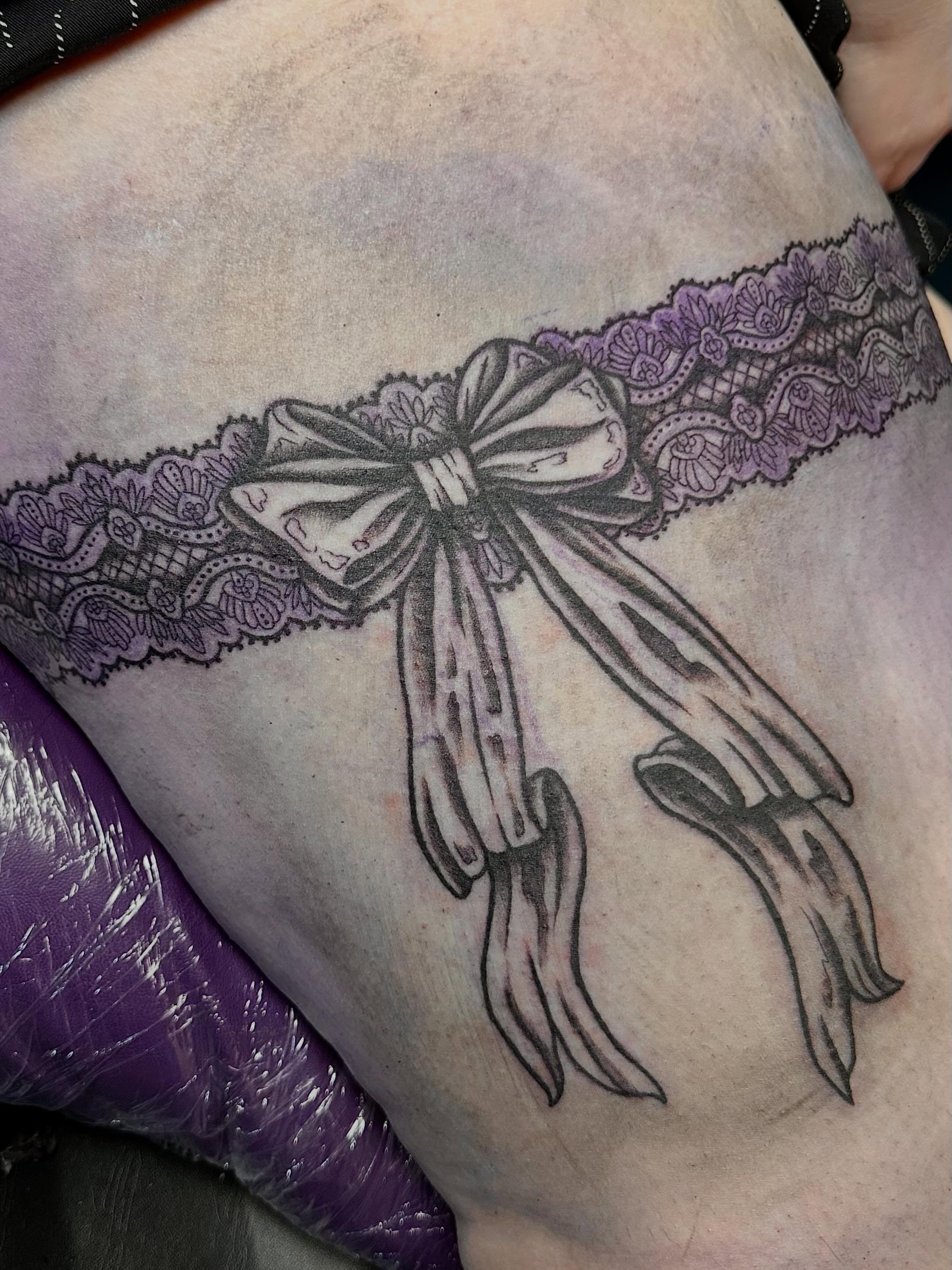 Lacy bow black and grey tattoo on the thigh by Mikaila Jean