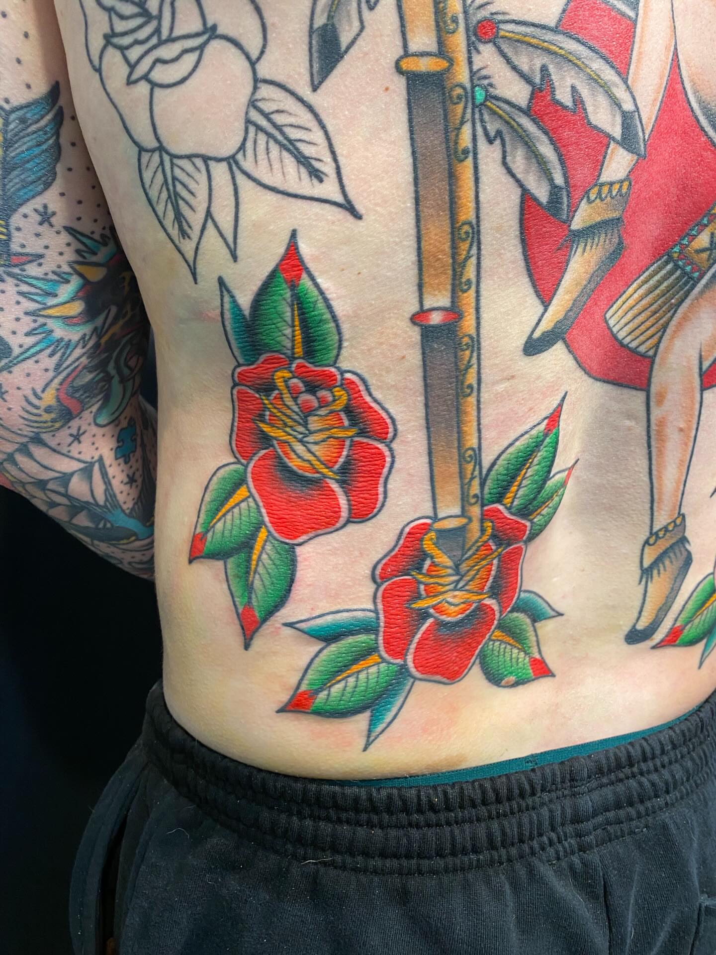 Red roses and sword American traditional tattoo on the ribs by Jarid Penn