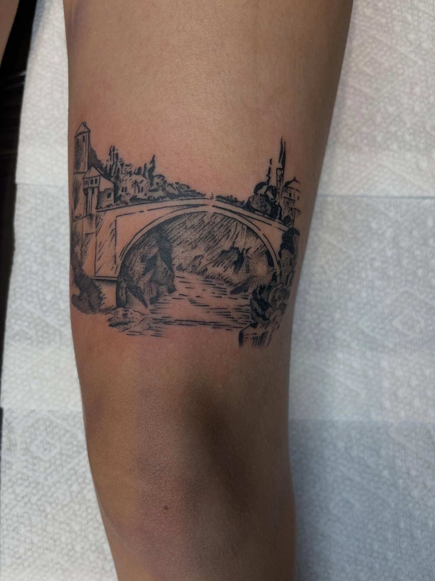 Bridge and landscape black and grey tattoo on the forearm by Evan Voelker