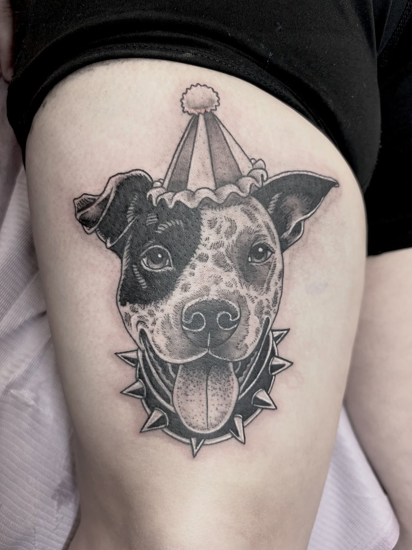 Pit bull with party hat black and grey tattoo on the thigh by <3 eve’s tattoos <3
