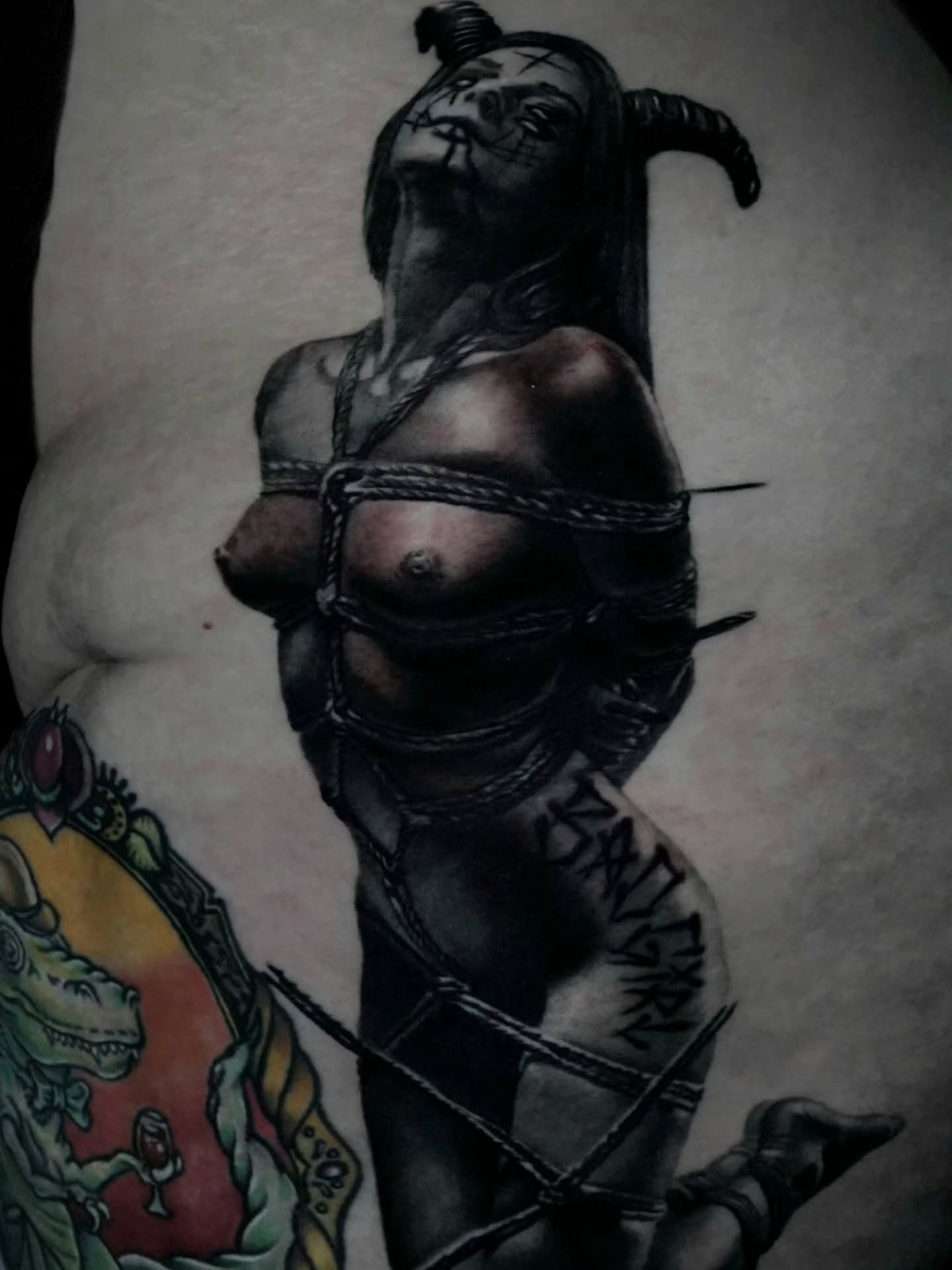 Bound woman dark realism tattoo on the torso by Dan Redding