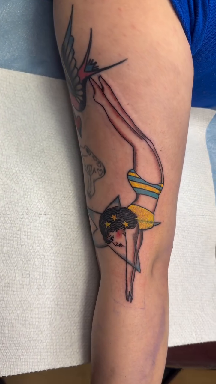 Diver with swallow and hearts neo-traditional tattoo on the upper arm by Giana Masso