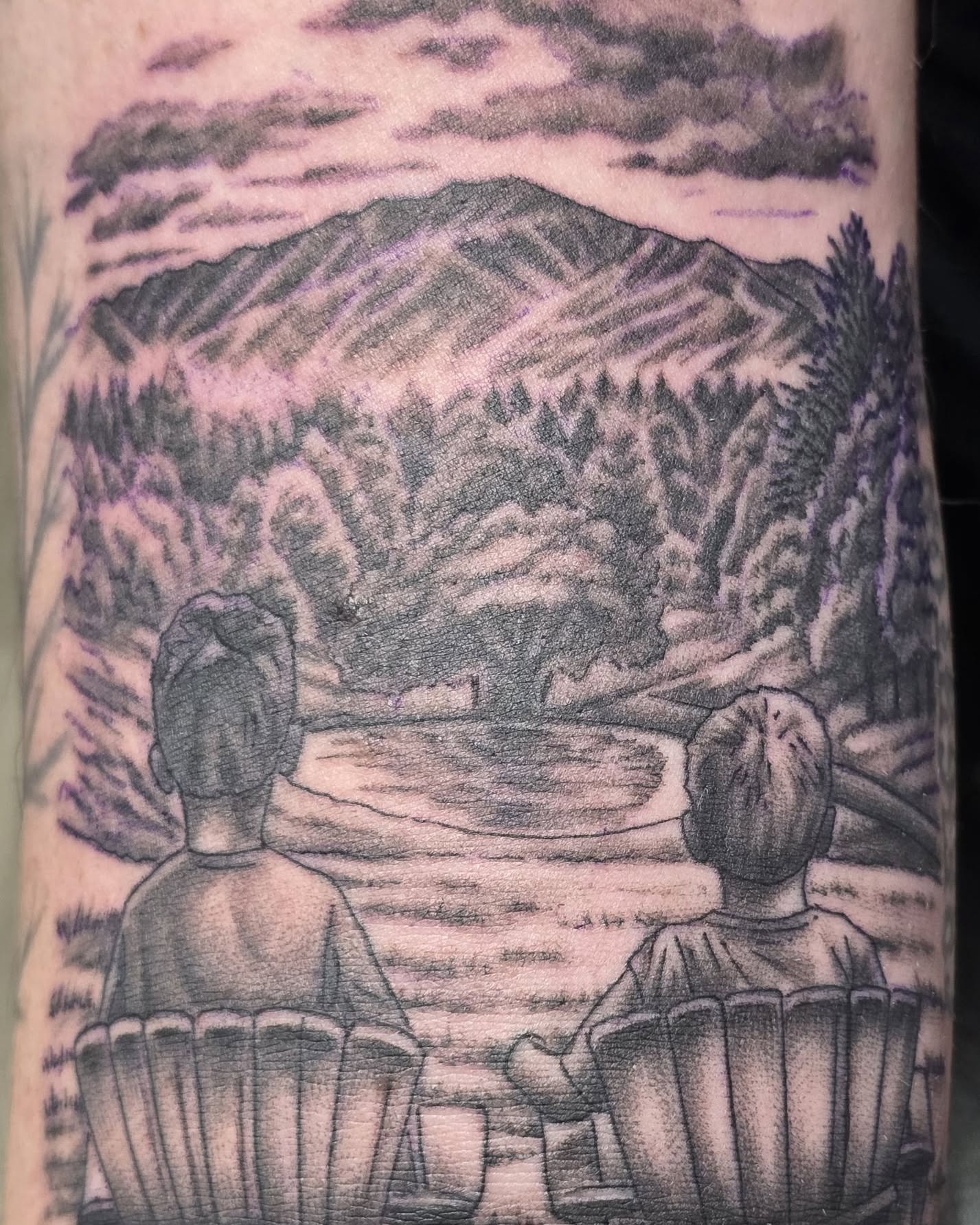 Mountain landscape black and grey tattoo on the upper arm by Gene Britton
