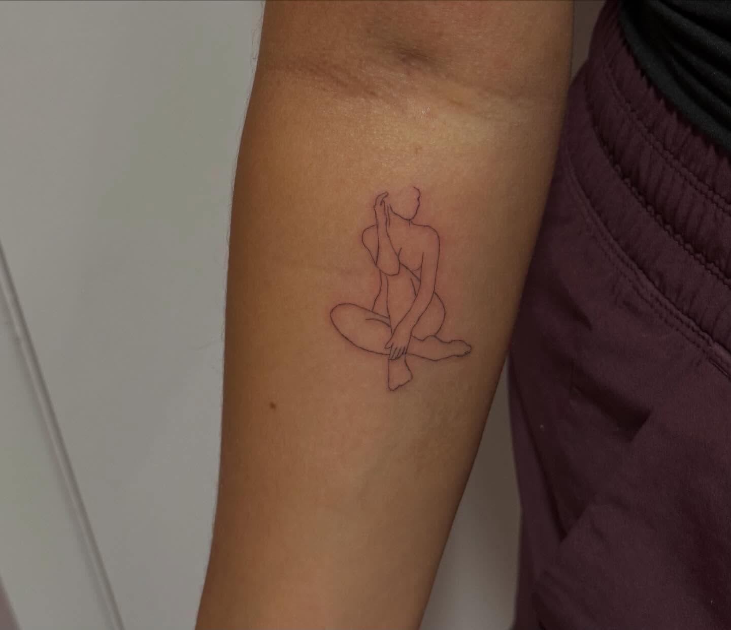 Seated figure minimalist tattoo on the forearm by Lexie Decker, Canton, Ohio