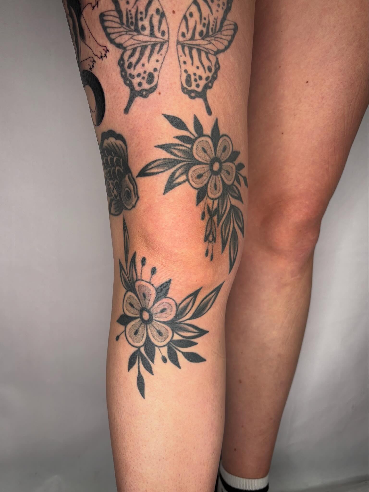 Butterflies and flowers black and grey tattoo on the leg by Victoria Bacon