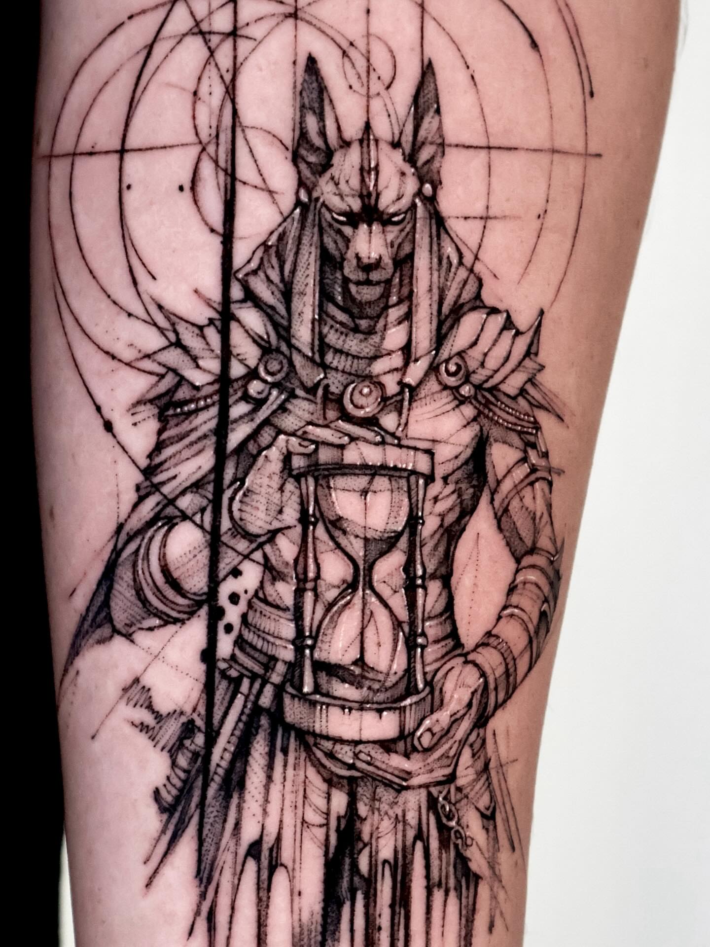 Ancient god with hourglass geometric tattoo on the forearm by Tadi