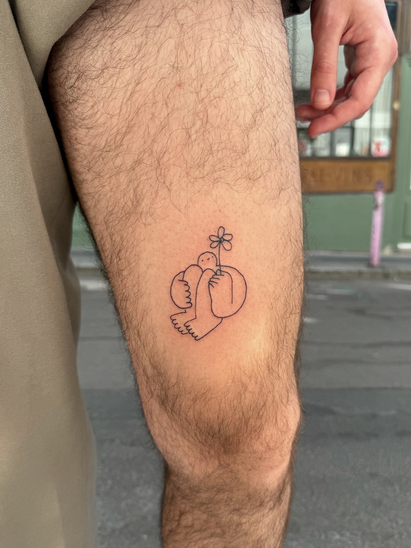 Bird holding flower minimalist tattoo on the thigh by Eden Kalif