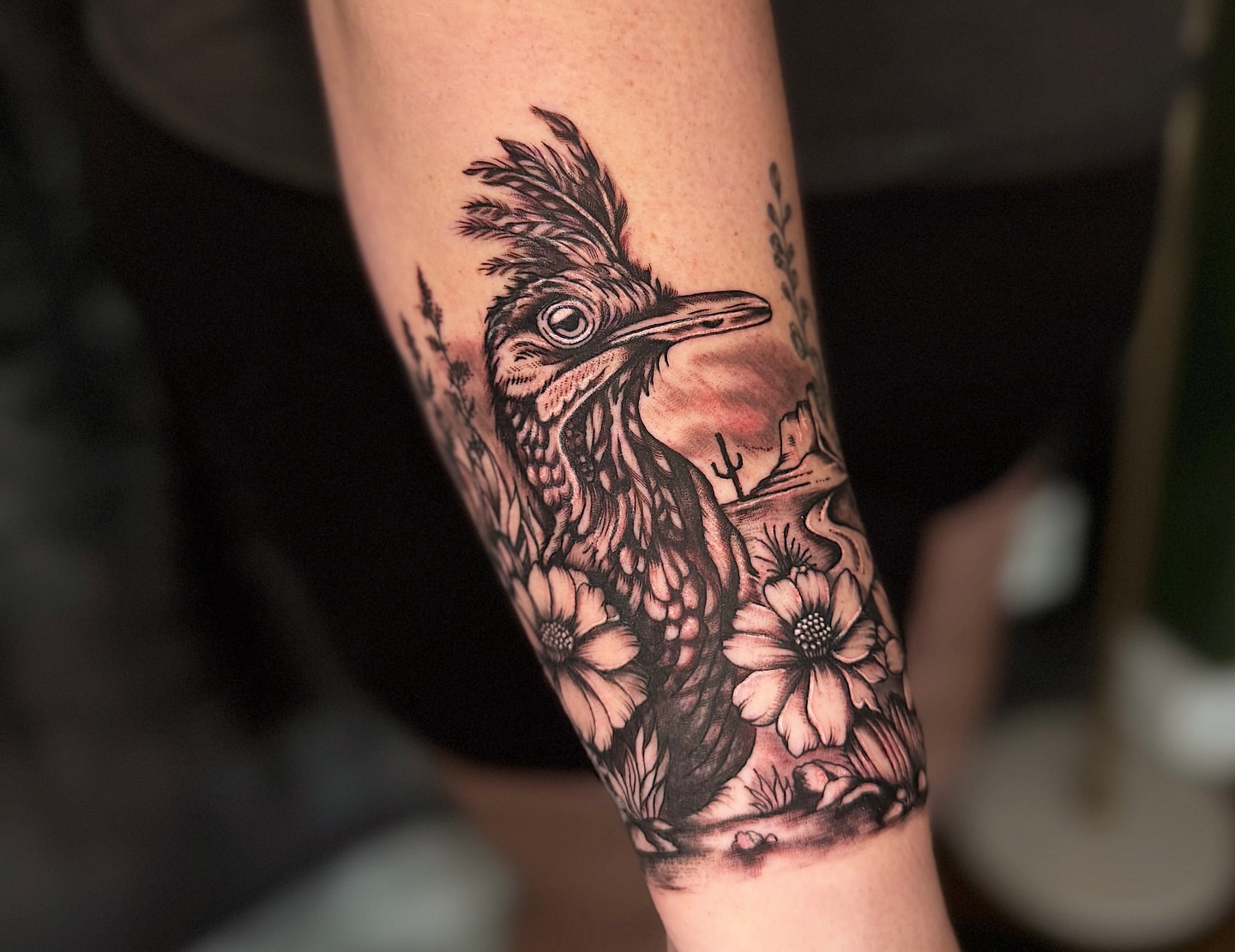 Roadrunner and flowers black and grey tattoo on the forearm by Breanna Werner
