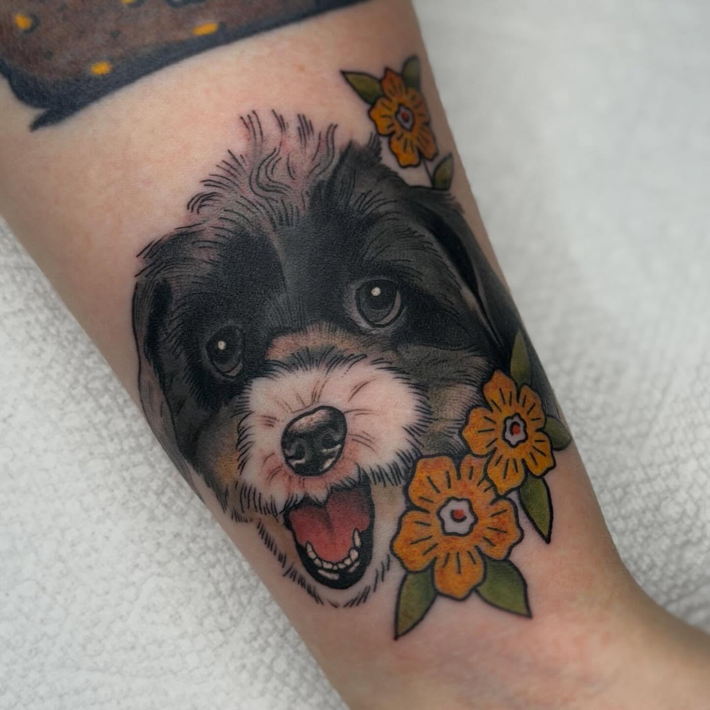 Dog with flowers realism tattoo on the forearm by Jenna Szerszen-Wynn ๐
