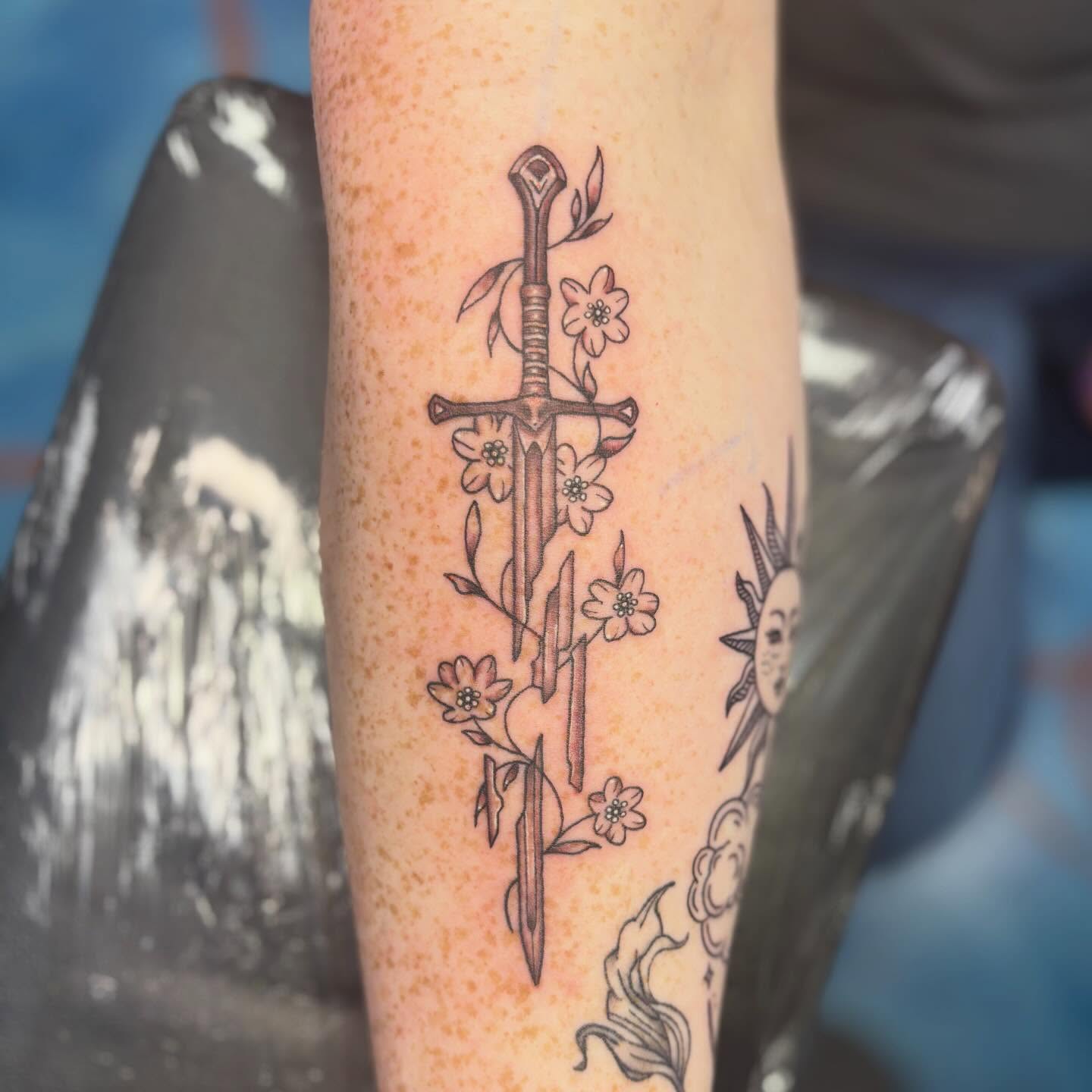 Sword and flowers neo-traditional tattoo on the forearm by Cam Sykes