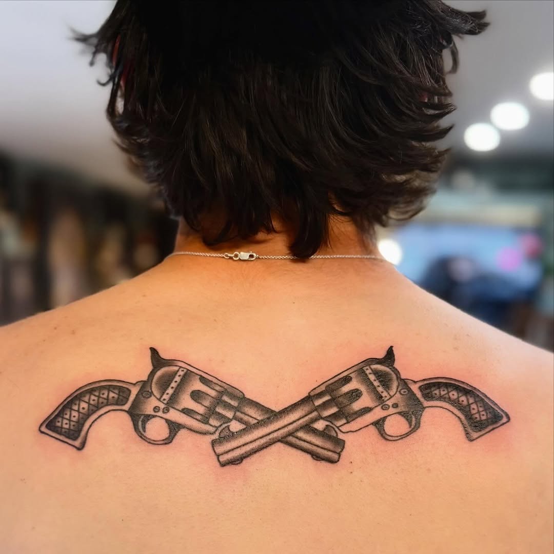 Crossed revolvers American traditional tattoo on the back by savannah
