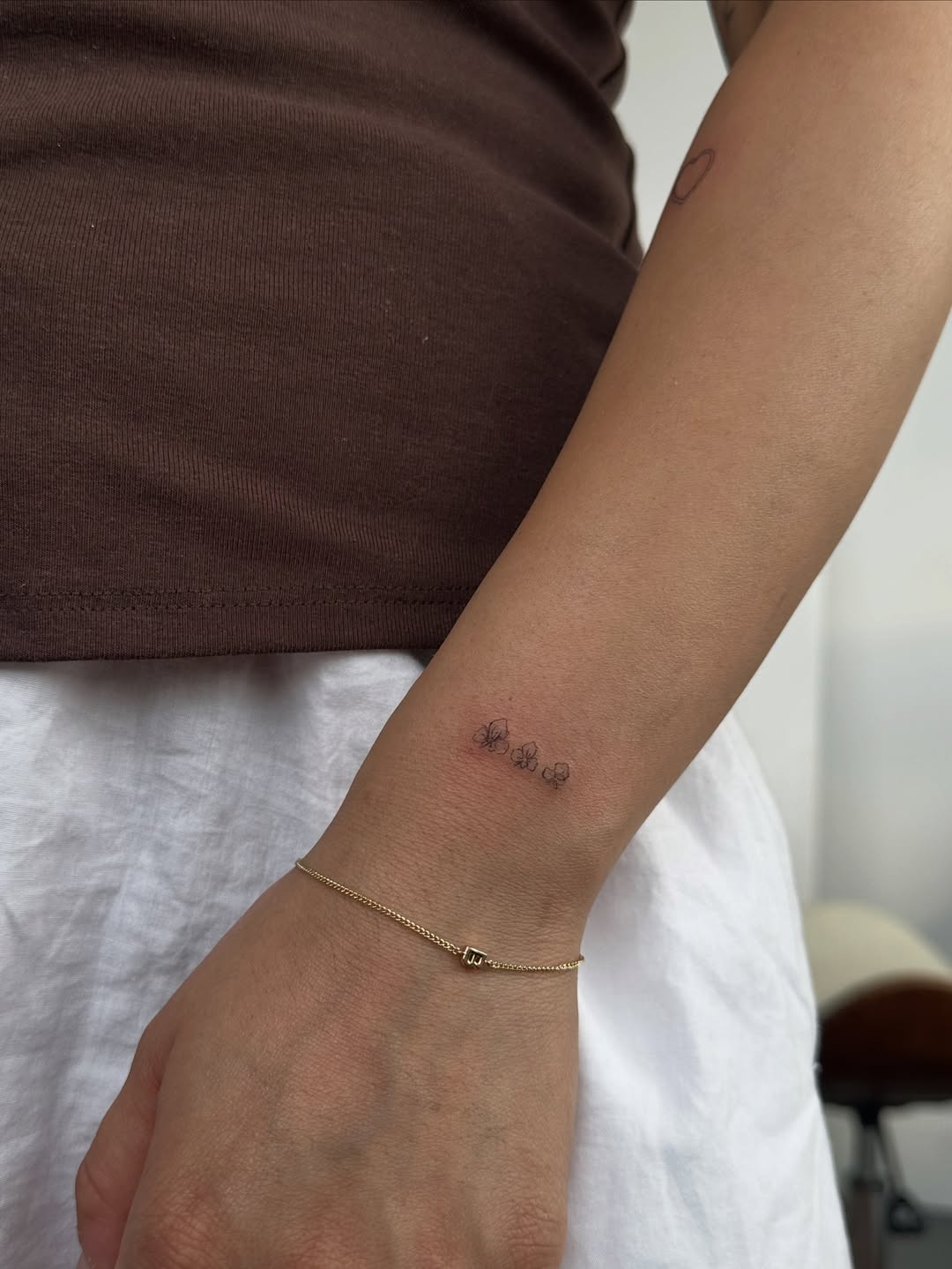 Three small flowers minimalist tattoo on the forearm by @taravychi