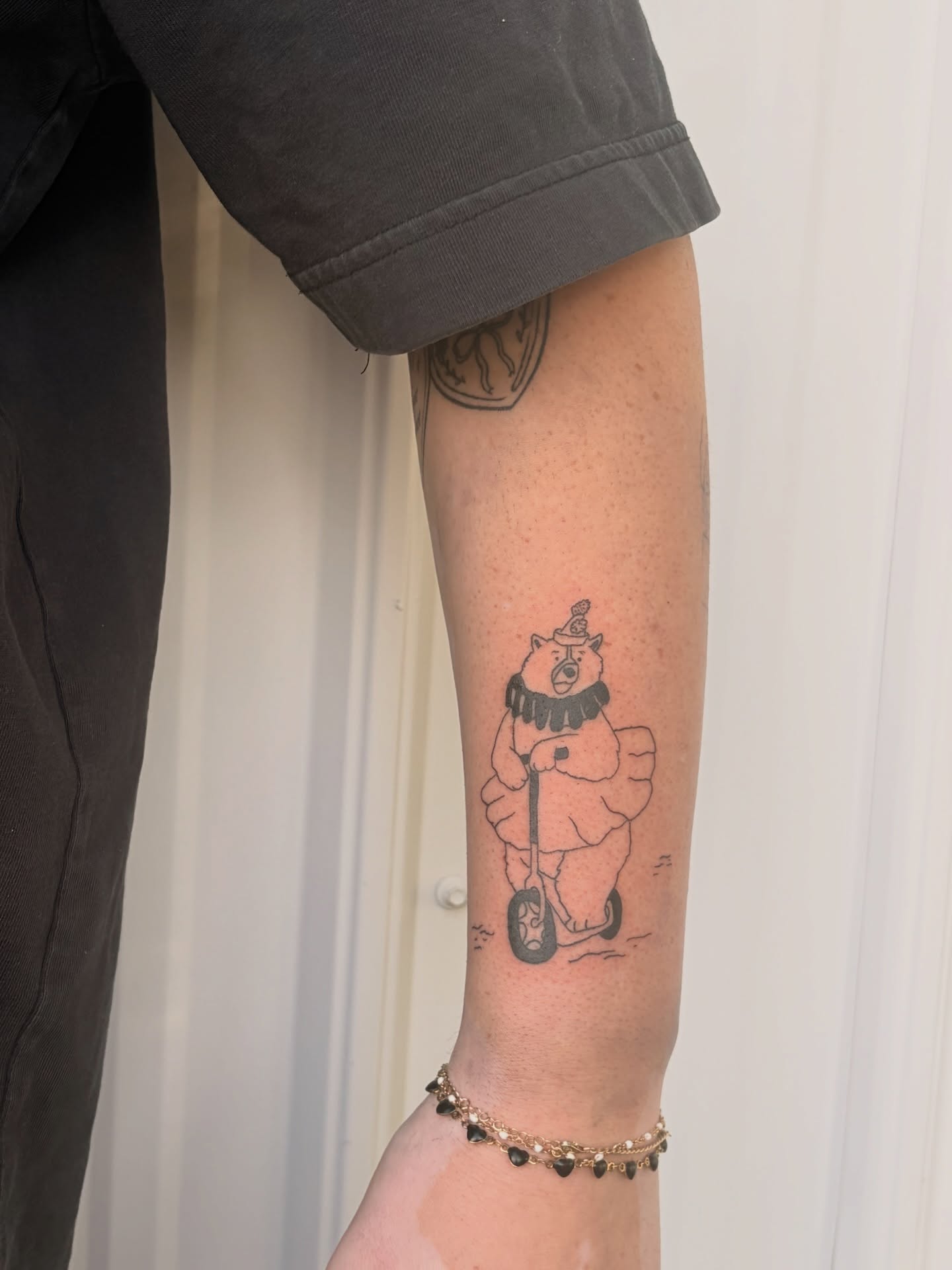Bear riding scooter black and grey tattoo on the forearm by Inky Birdz Tattoos
