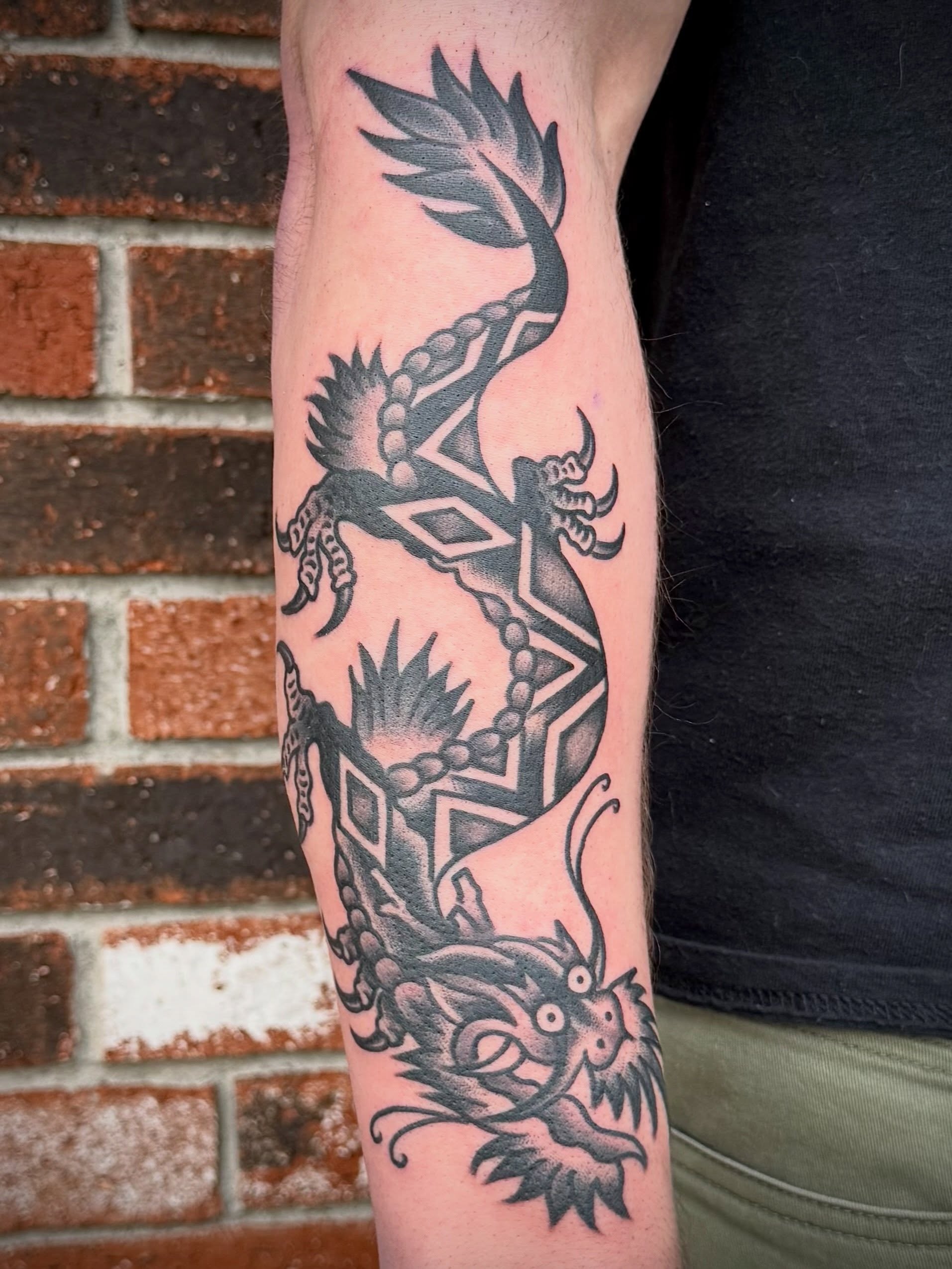 Dragon black and grey tattoo on the forearm by Maximilian Harrison