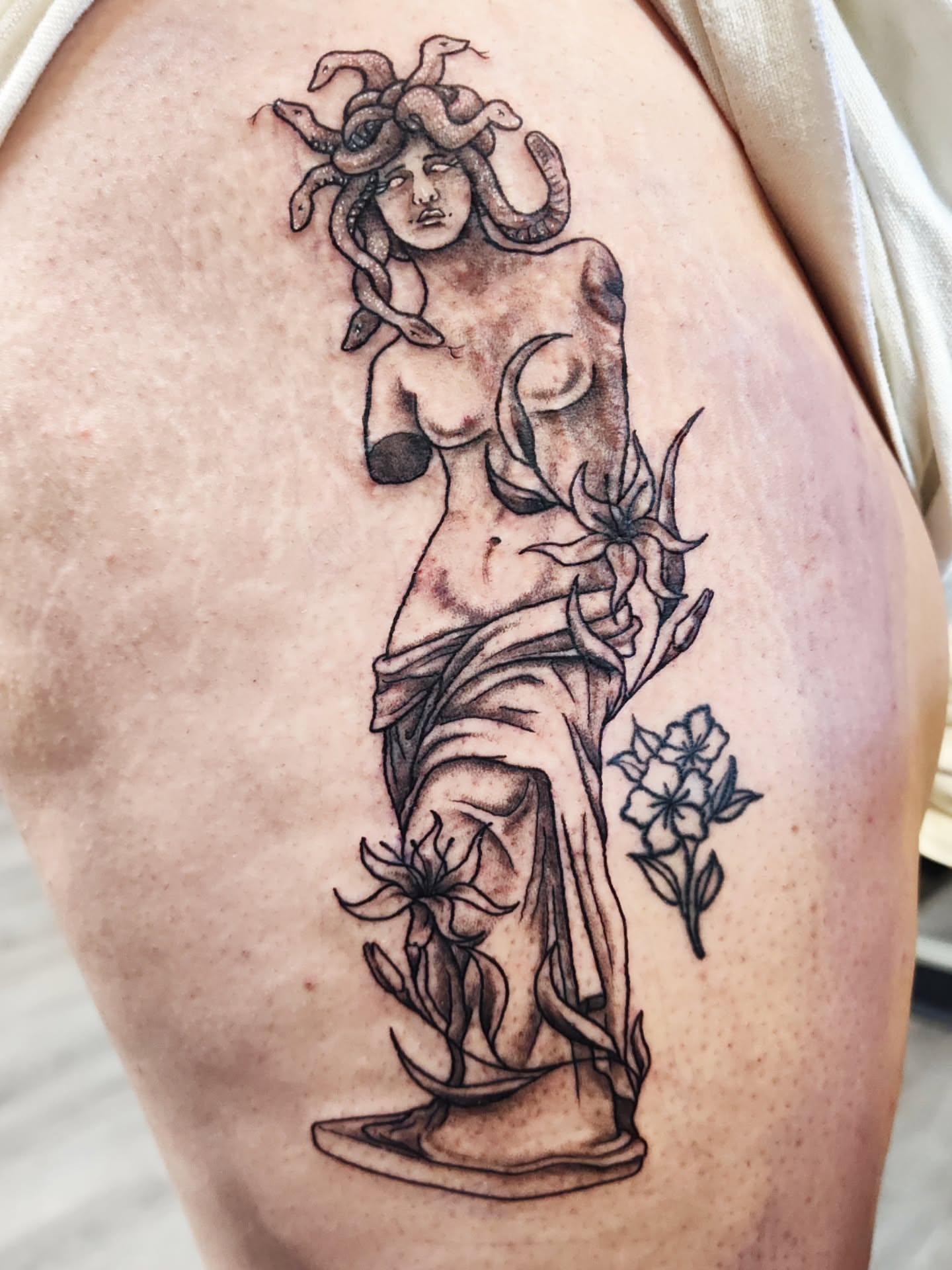 Medusa statue black and grey tattoo on the thigh by Mercury