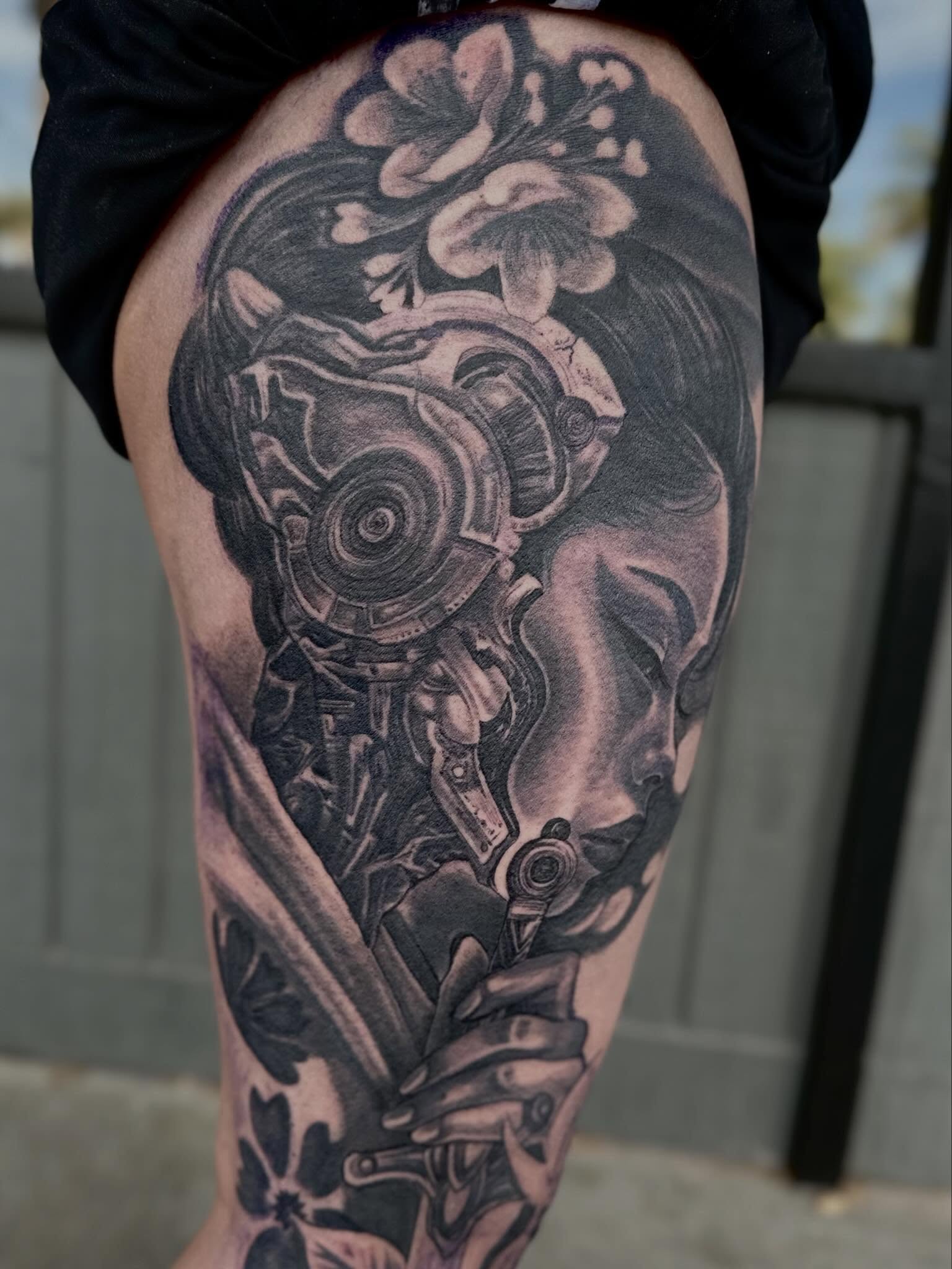 Cyborg head with floral elements realism tattoo on the thigh by Mathilda Quynh