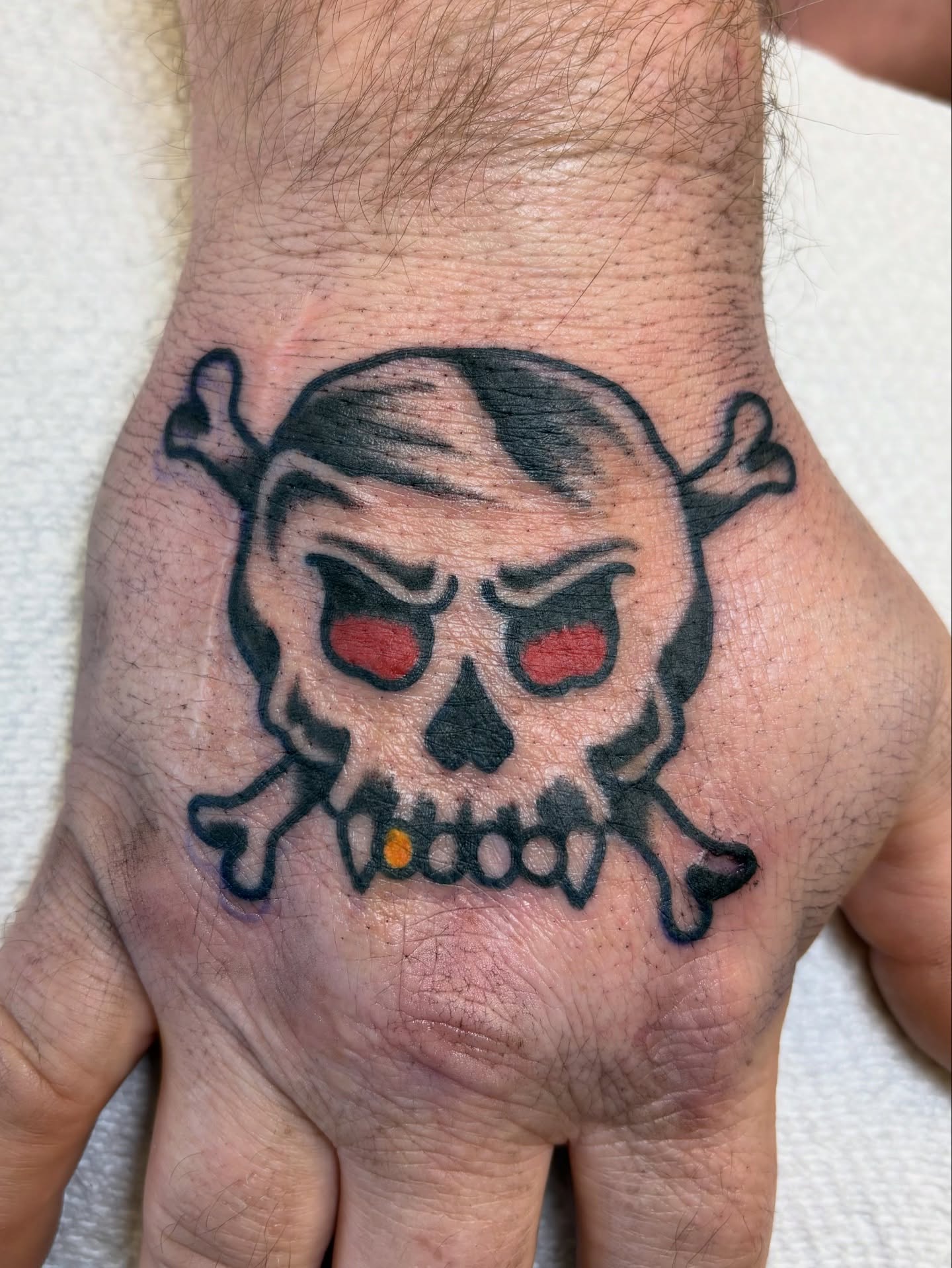 Skull and crossbones American traditional tattoo on the hand by Jake Herbert, Knoxville, Tennessee