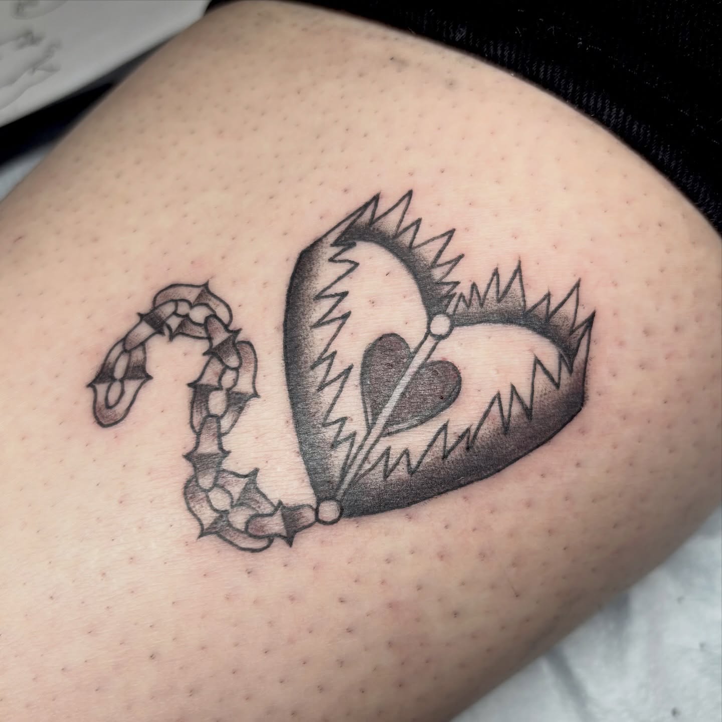 Heart with thorns black and grey tattoo on the thigh by Weho Tattoo Artist Lupe