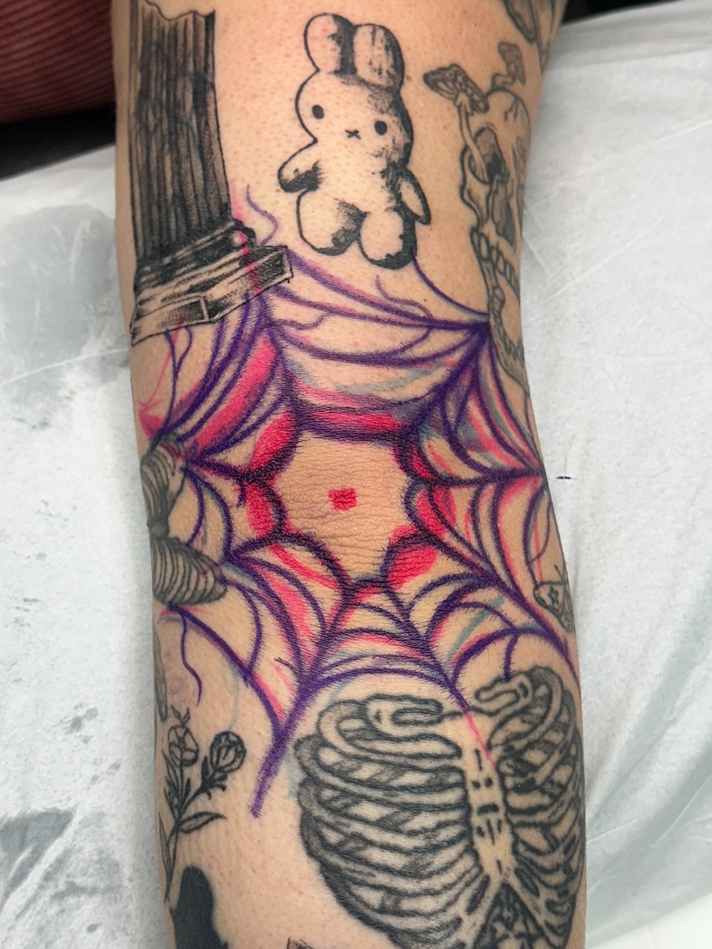 Spiderweb and bunny geometric tattoo on the forearm by Halle Cooper