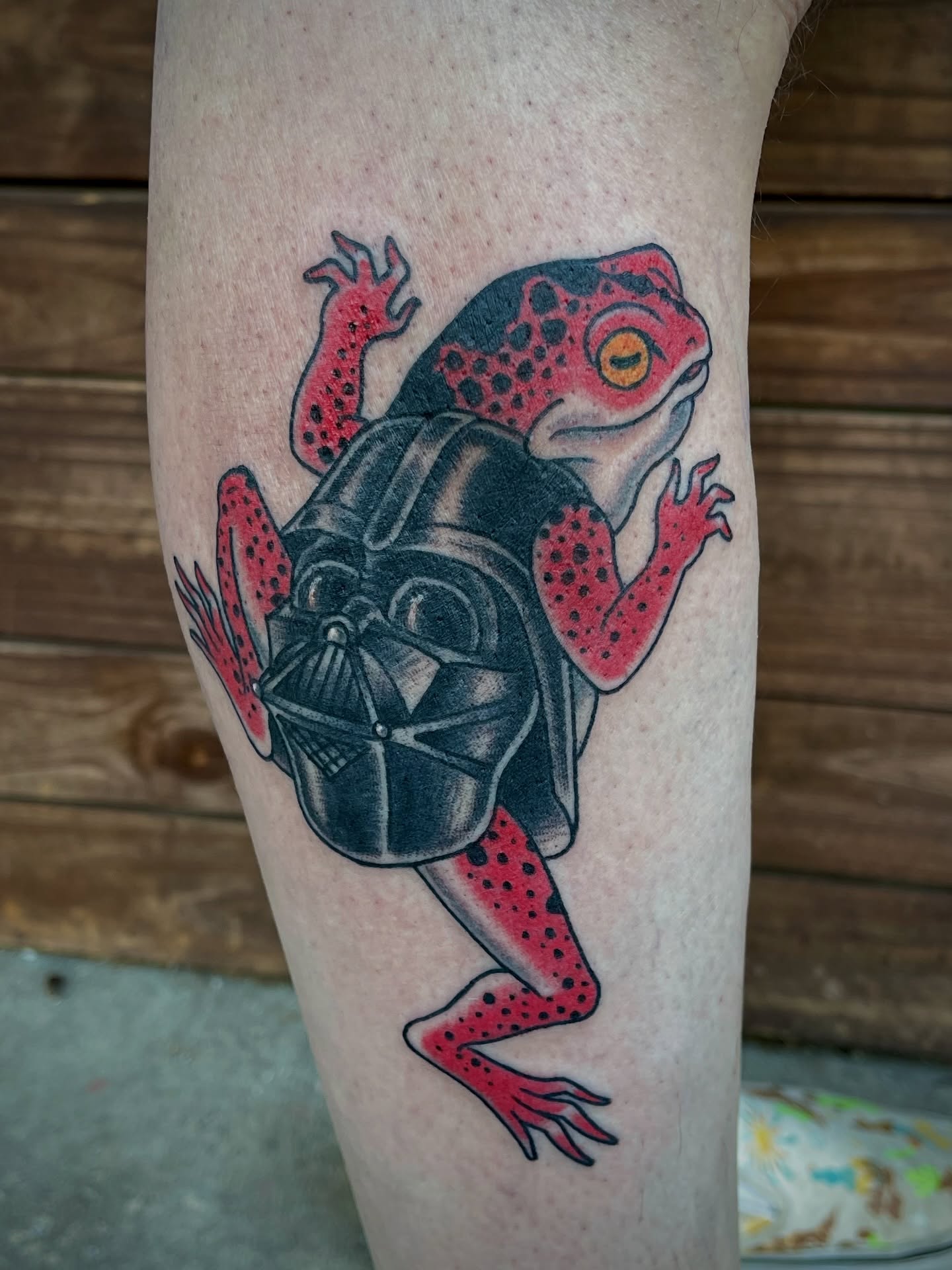 Frog with Darth Vader helmet trash polka tattoo on the forearm by Thad Collis