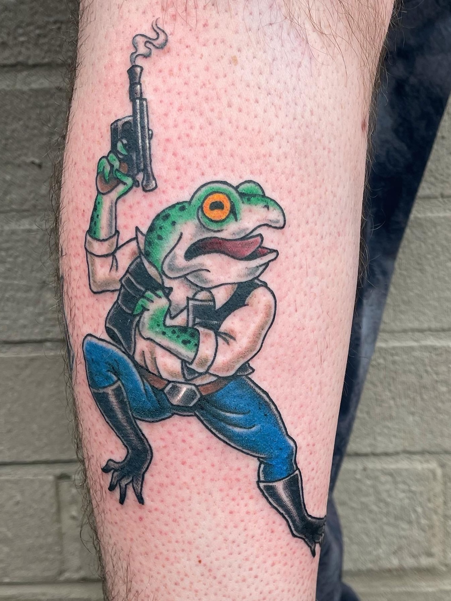 Frog with gun new school tattoo on the forearm by Thad Collis