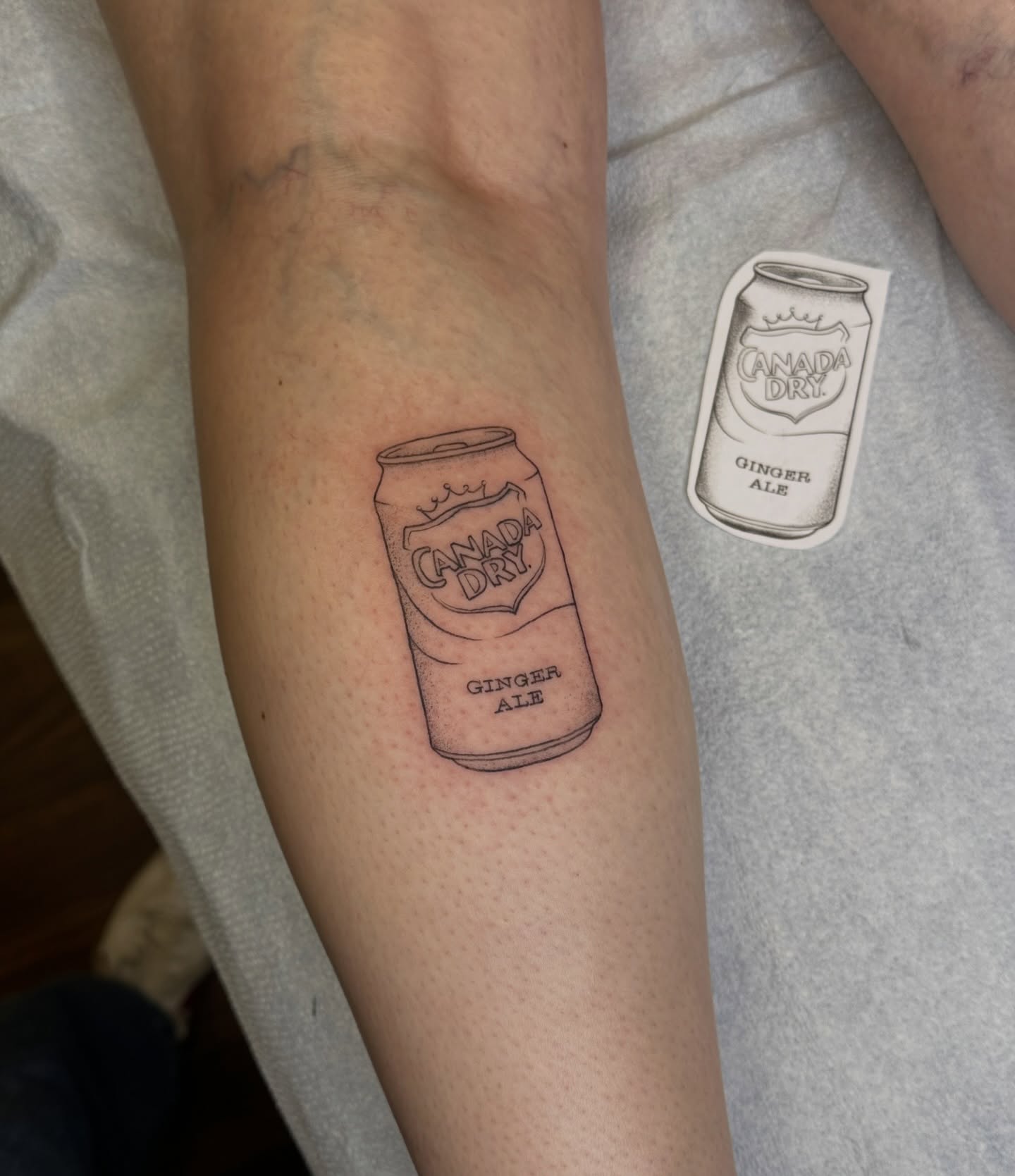 Can of Canada Dry ginger ale black and grey tattoo on the forearm by Lauren