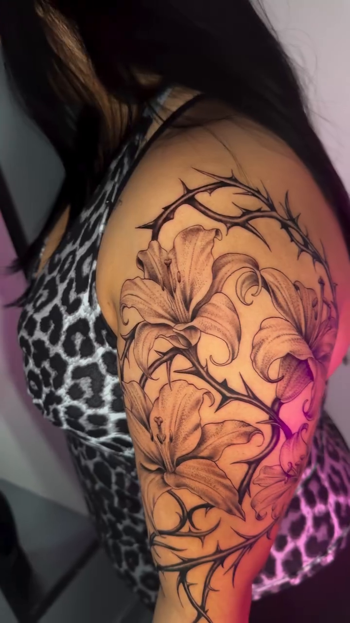 Lilies and thorns fine line tattoo on the thigh by Monica Gonzalez