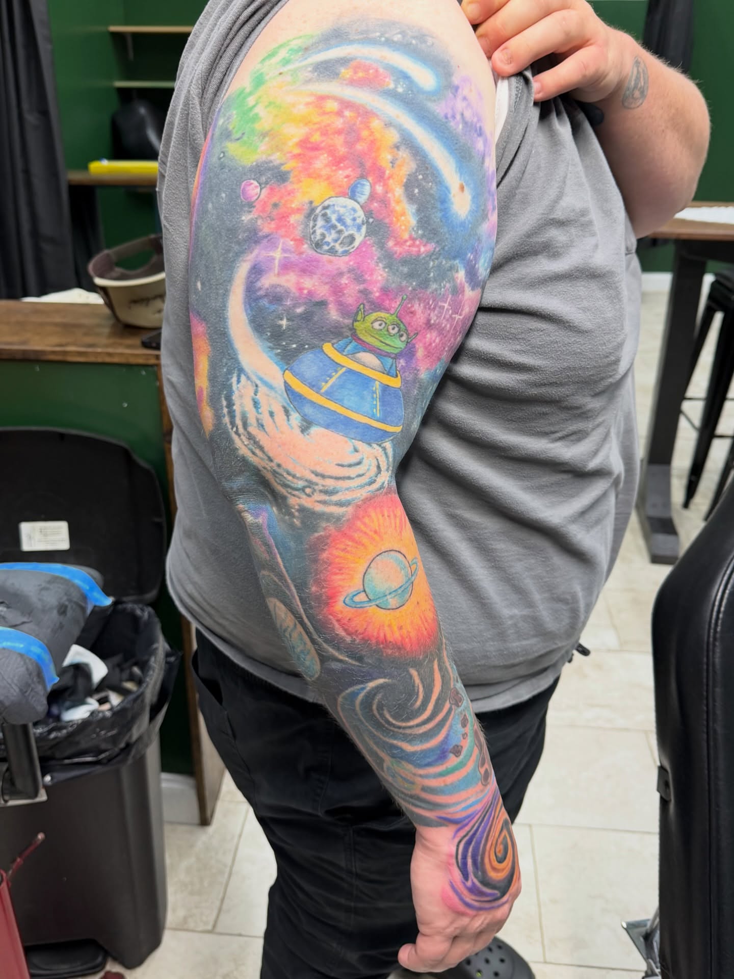 Space-themed astronaut new school tattoo on the upper arm by Squid