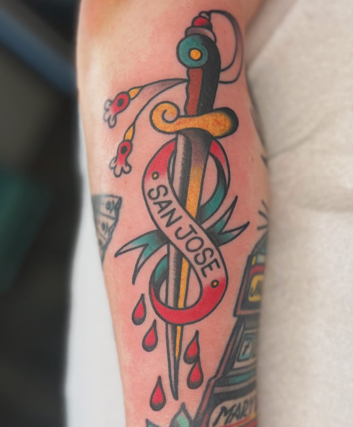 Sword and ribbon American traditional tattoo on the forearm by Mikey Montoya