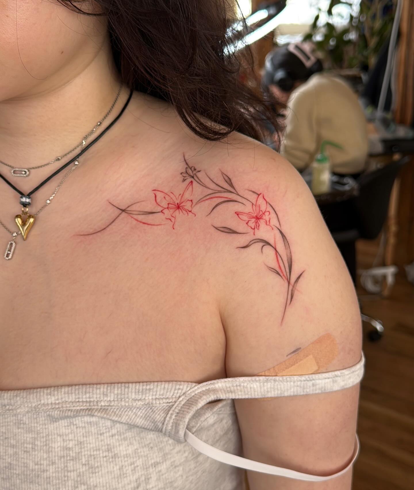 Floral design fine line tattoo on the shoulder by Ethan