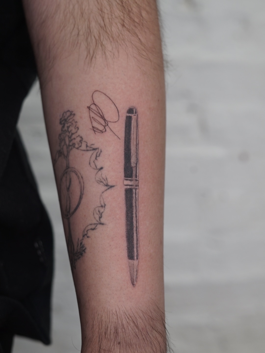 Pen and floral black and grey tattoo on the forearm by Josh Infante