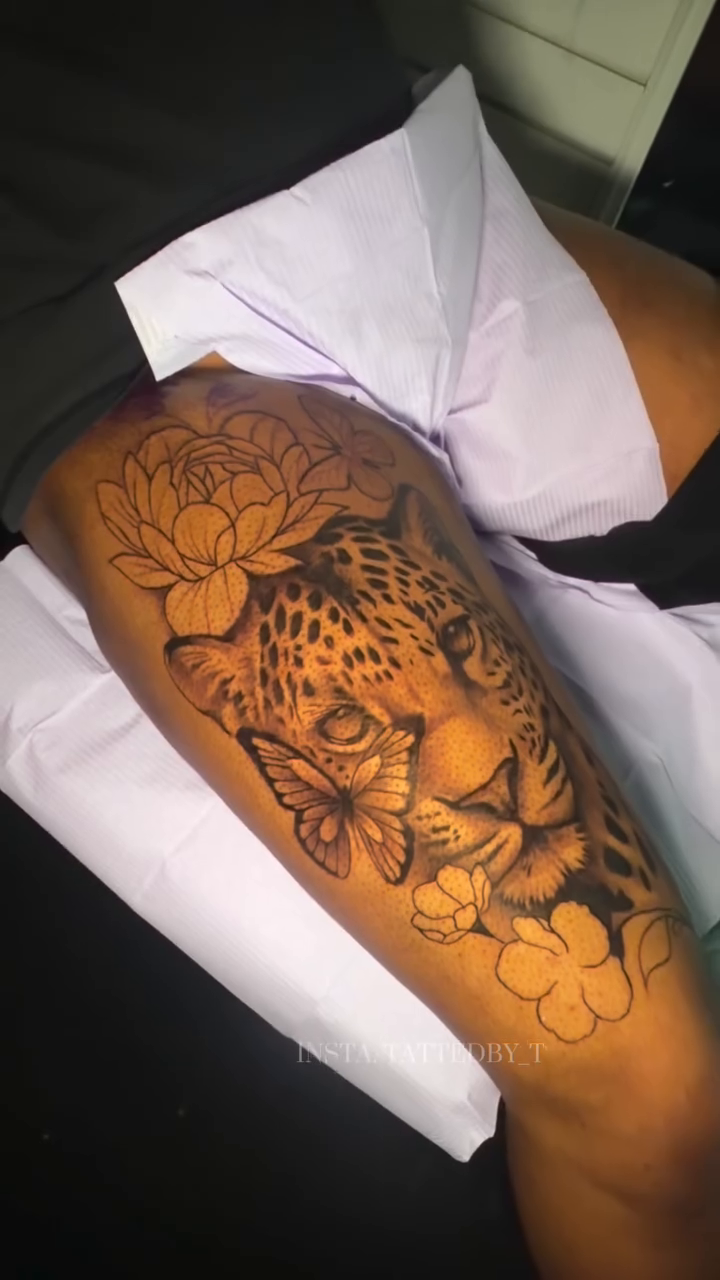 Leopard face with flowers and butterflies realism tattoo on the forearm by Female Cleveland Tat Artist ๐