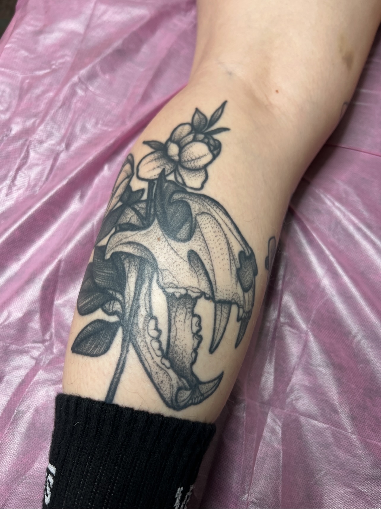 Skull with flowers dotwork tattoo on the forearm by Bri Leflore