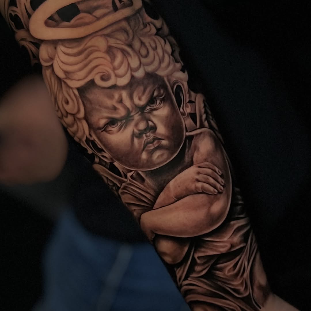 Grumpy cherub realism tattoo on the upper arm by ⚜️Lalo Godina Tattoo⚜️
