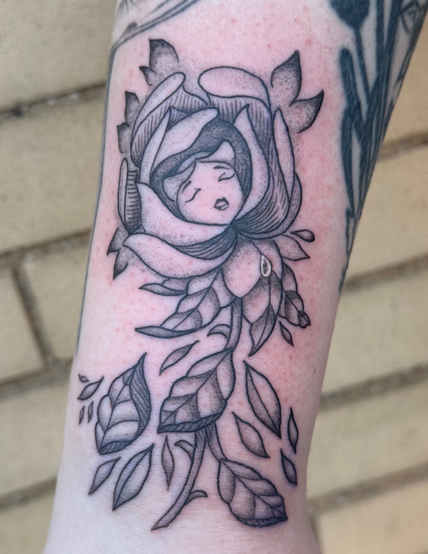 Flower with woman black and grey tattoo on the forearm by Mo