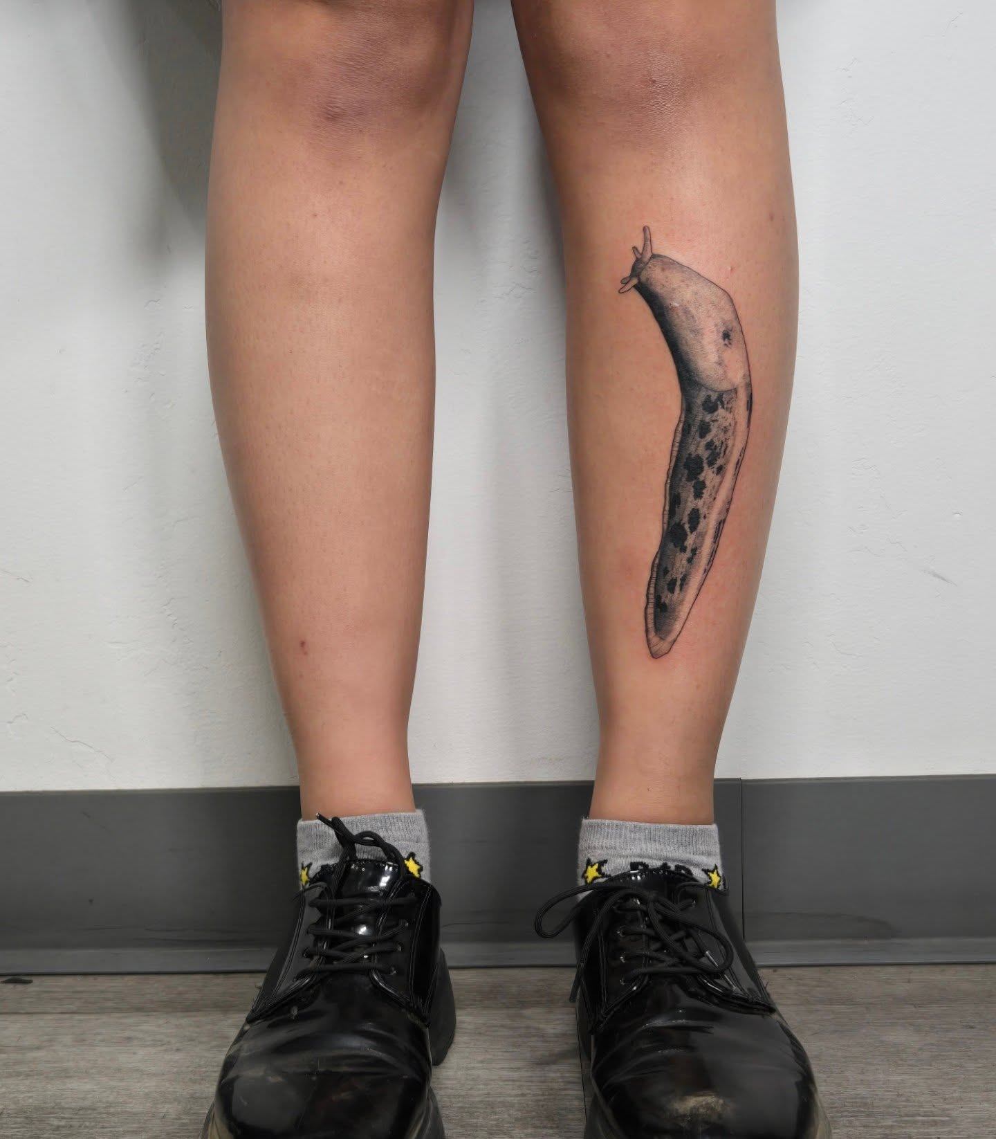Slug black and grey tattoo on the calf by alec