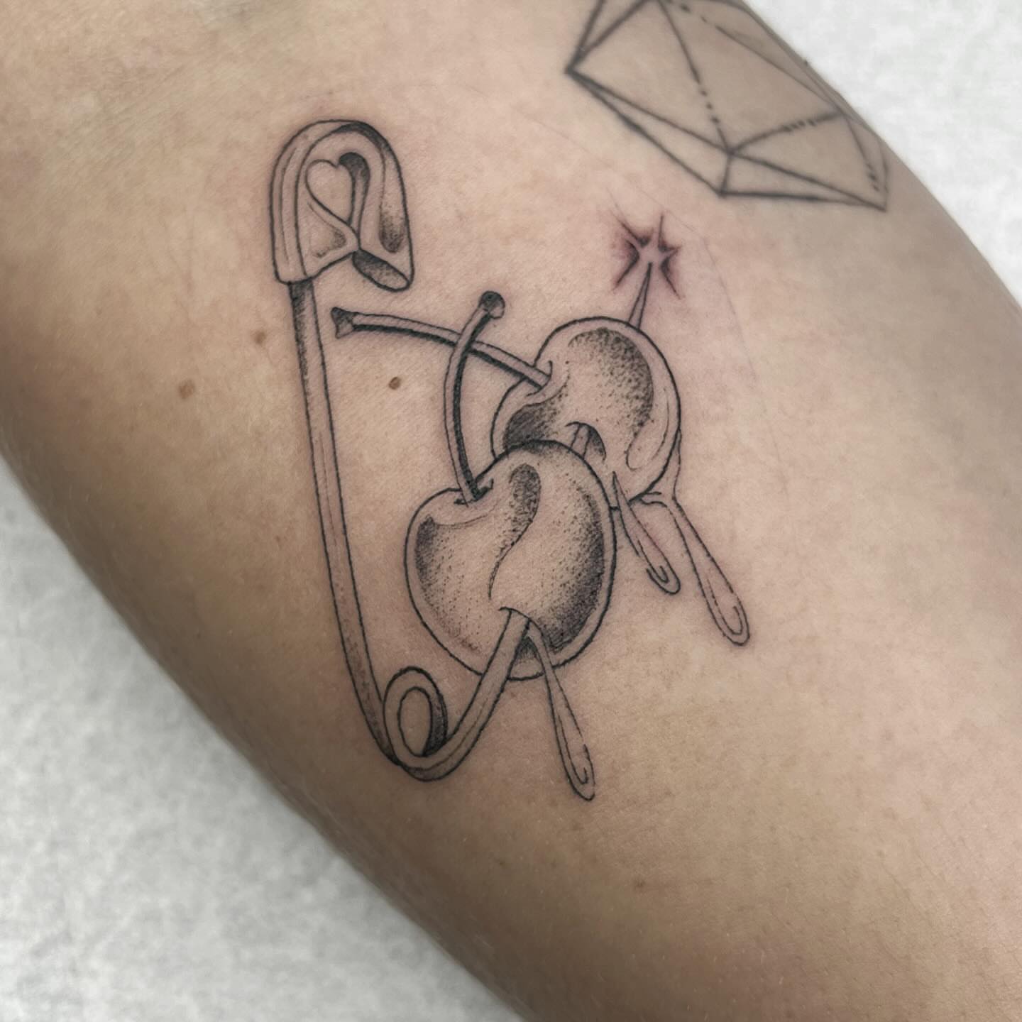 Heart and safety pin black and grey tattoo on the forearm by Sara Atamian, San Diego, California