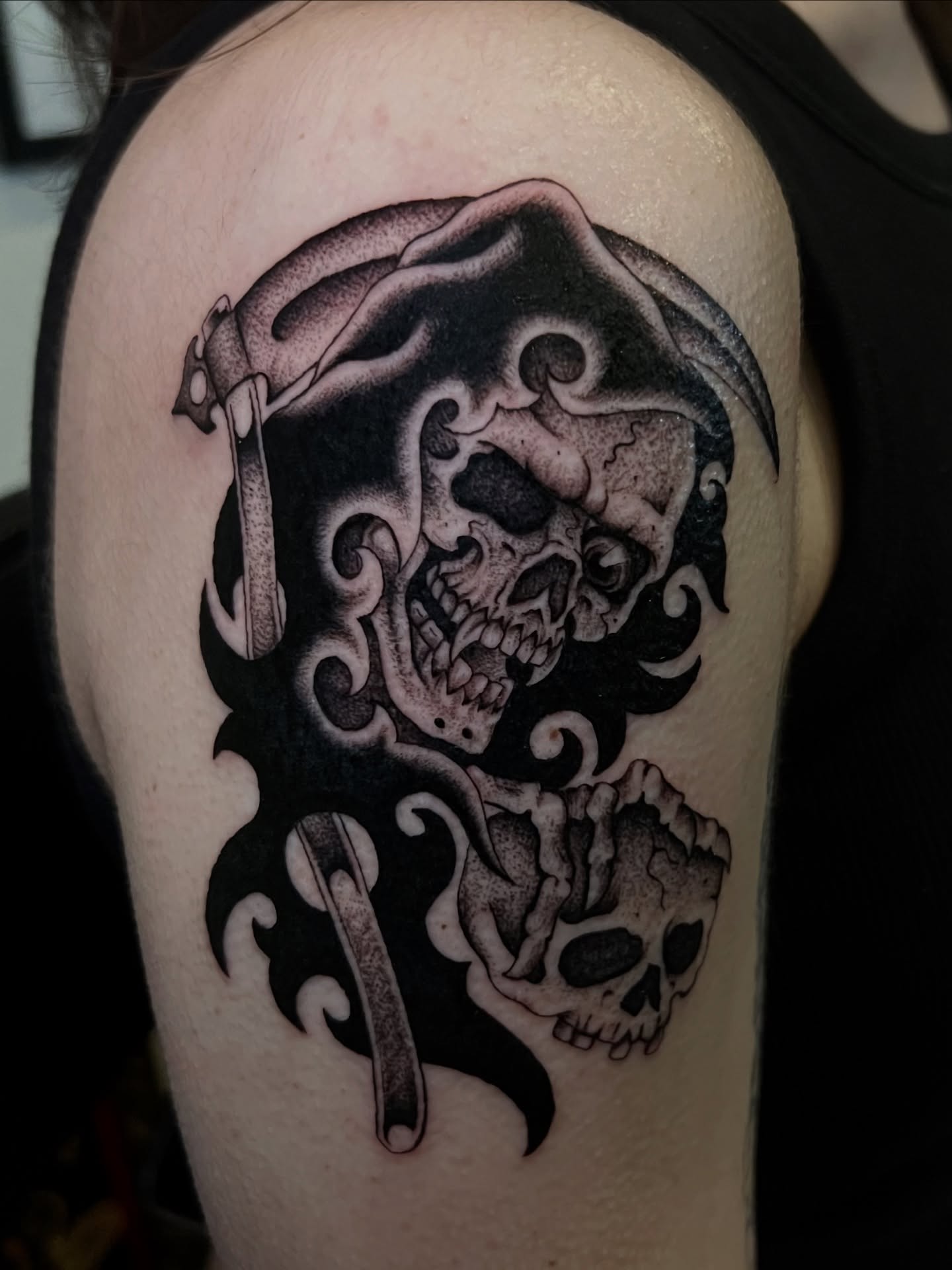 Skull and scythe tribal tattoo on the shoulder by Cassidy Maples